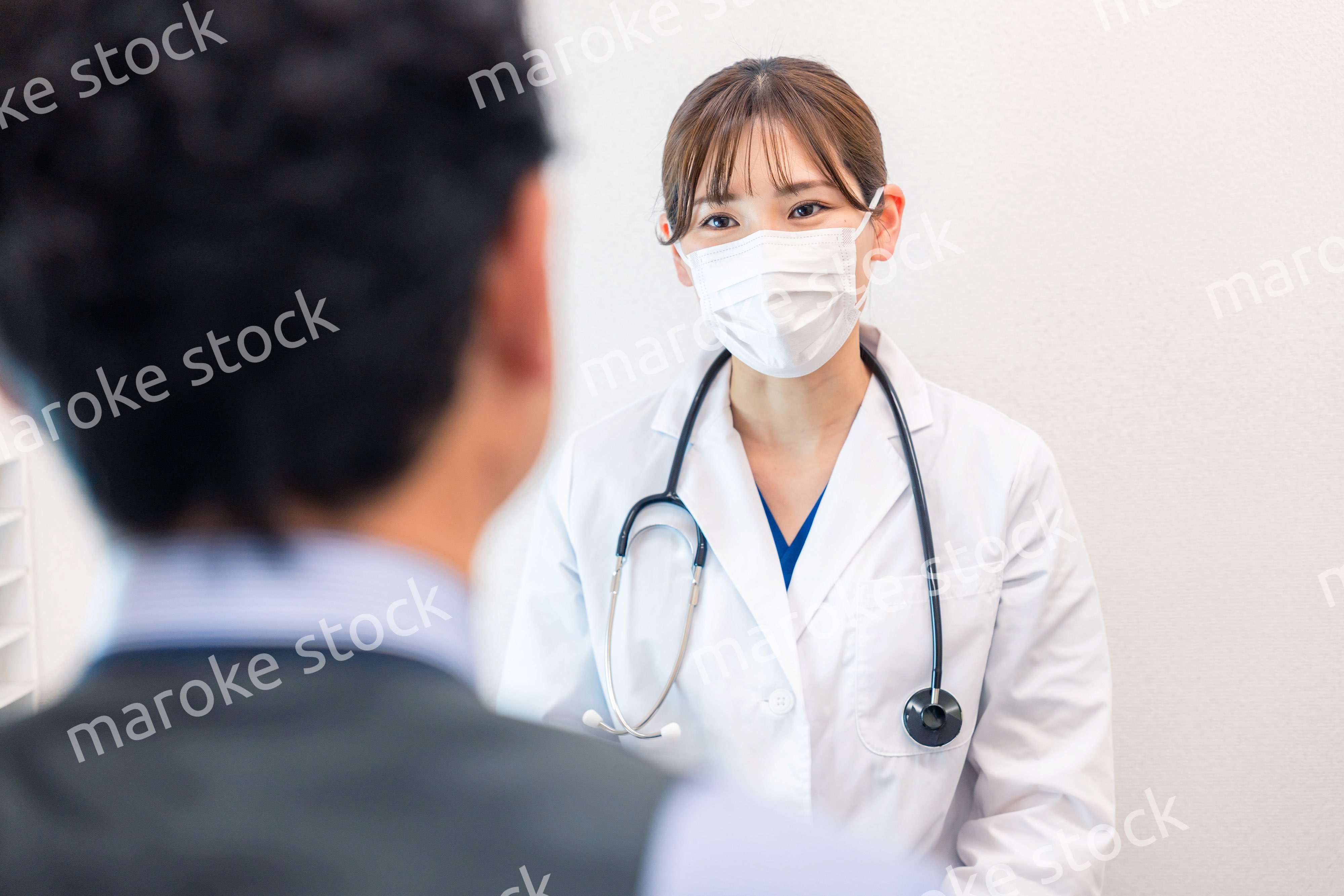 病院で男性患者の問診をする女性医師