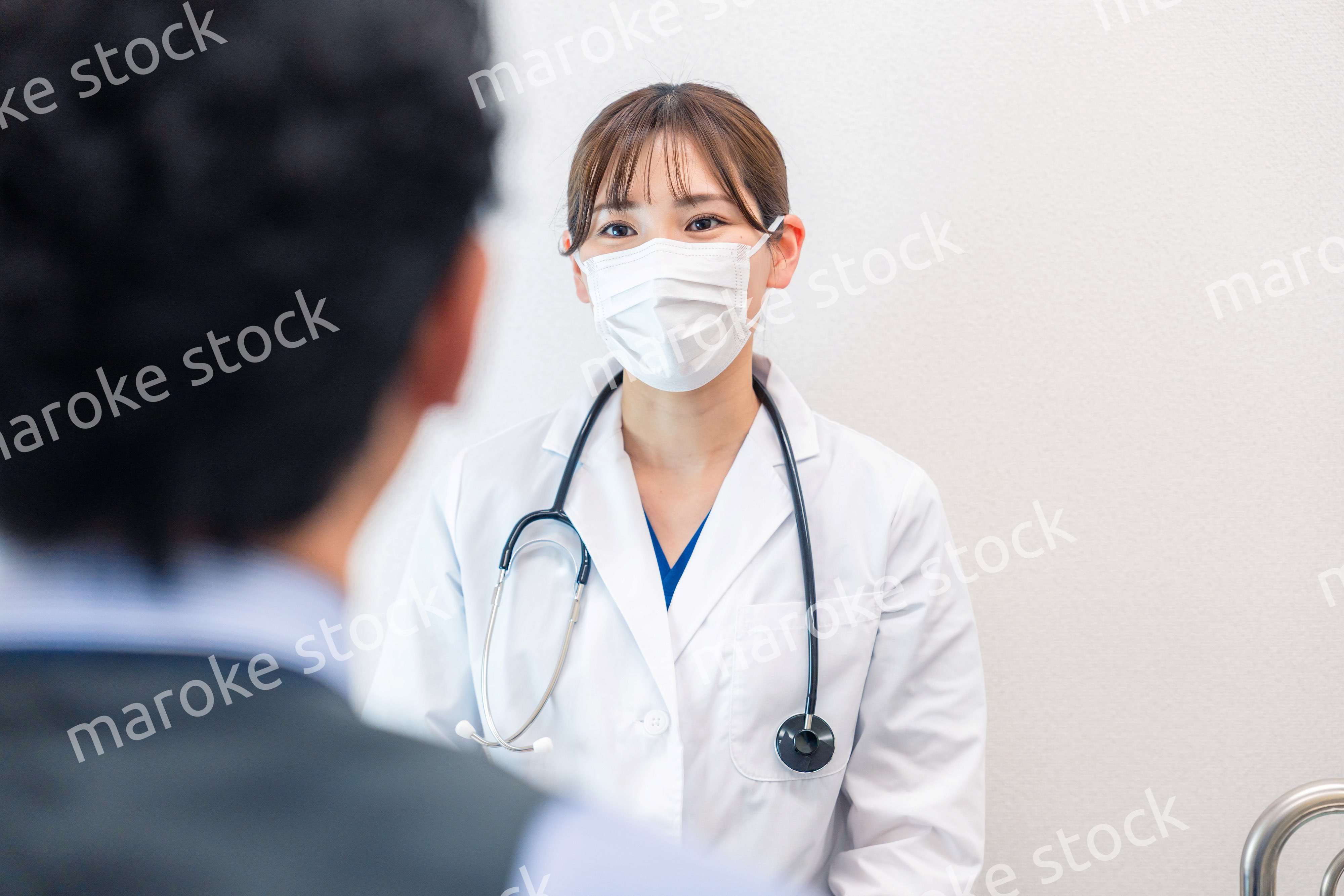 病院で男性患者の問診をする女性医師