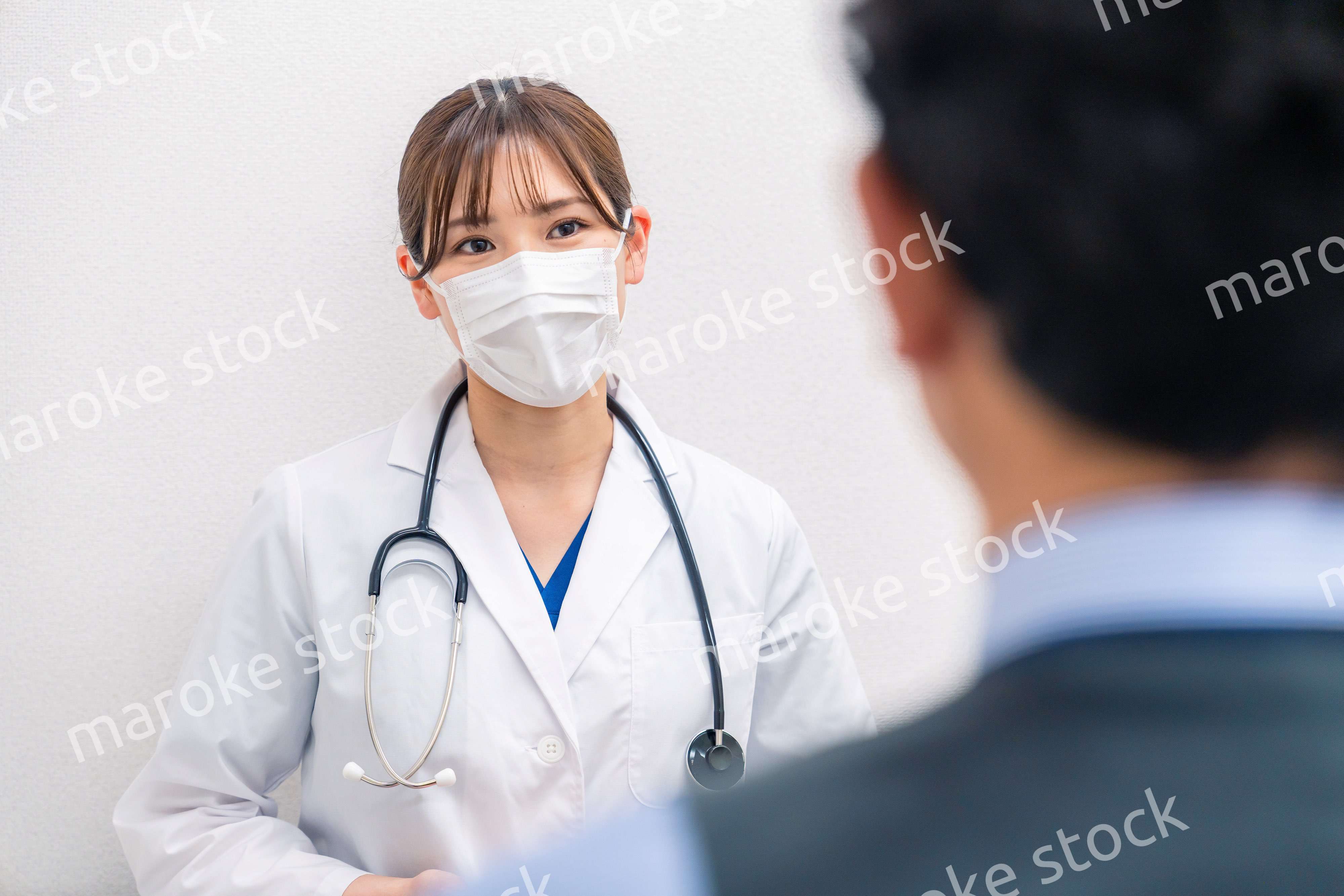 病院で男性患者の問診をする女性医師