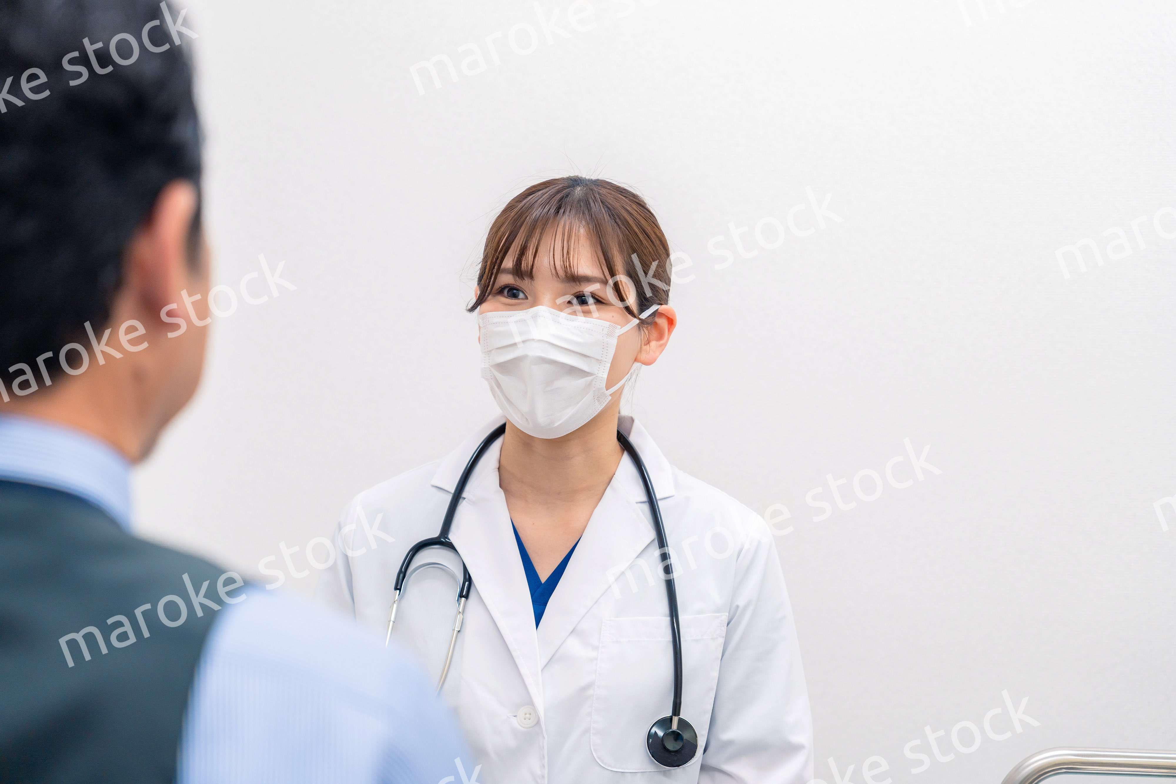 病院で男性患者の問診をする女性医師