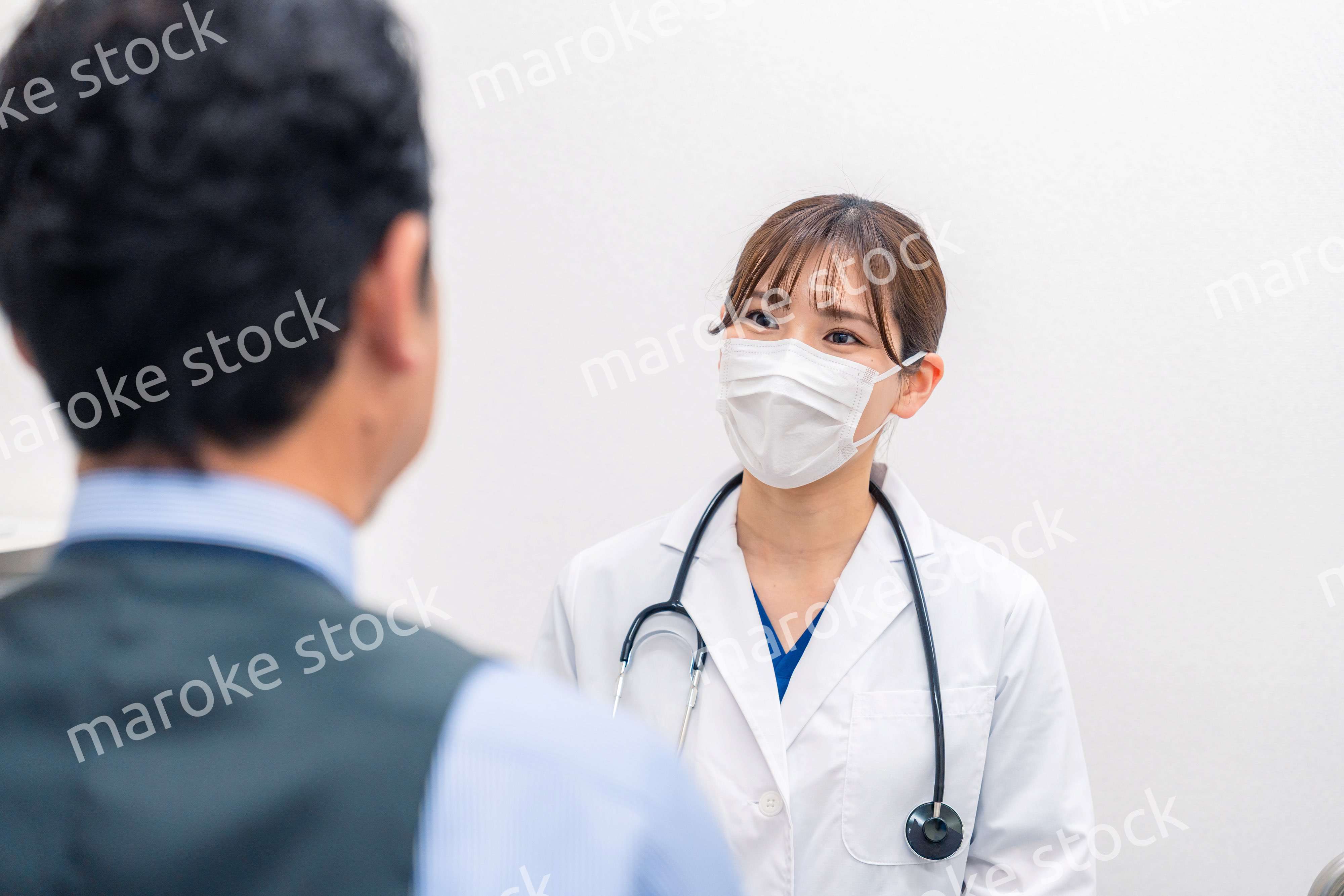 病院で男性患者の問診をする女性医師