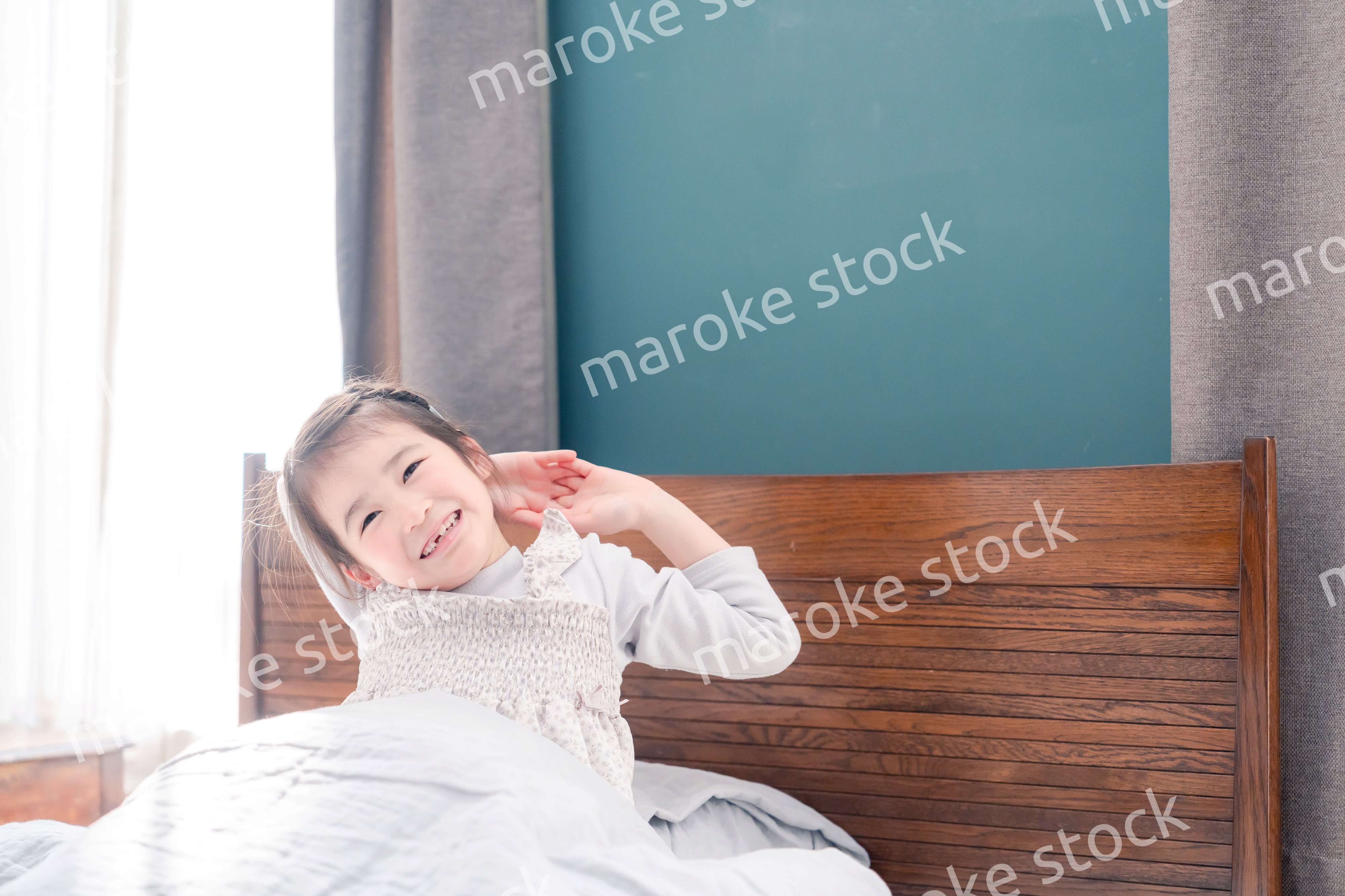 朝ベッドで目覚めて伸びをする小さな女の子