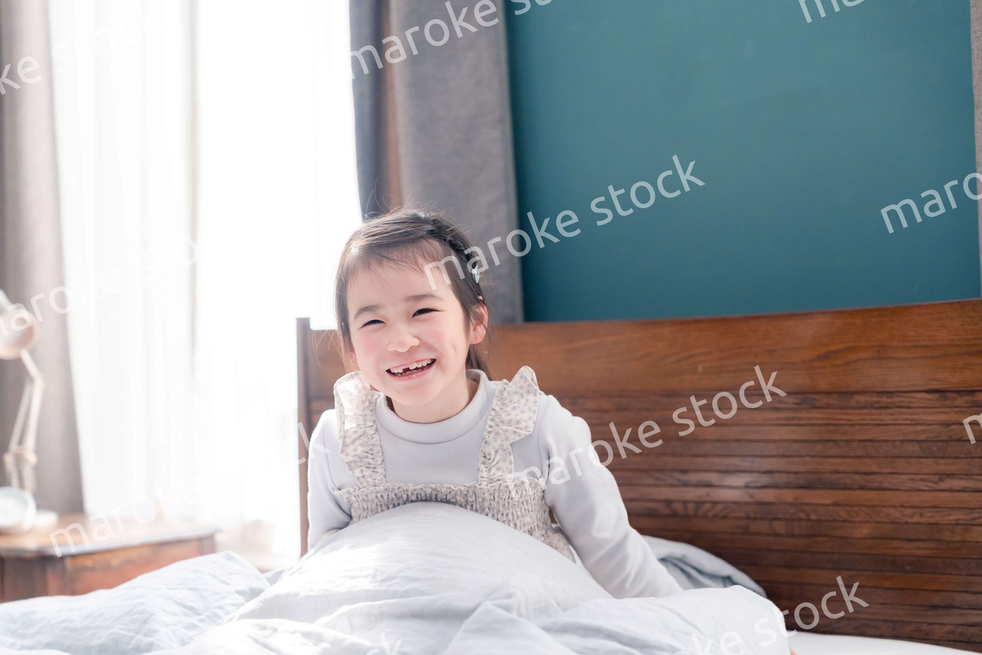 朝ベッドで目覚めて伸びをする小さな女の子