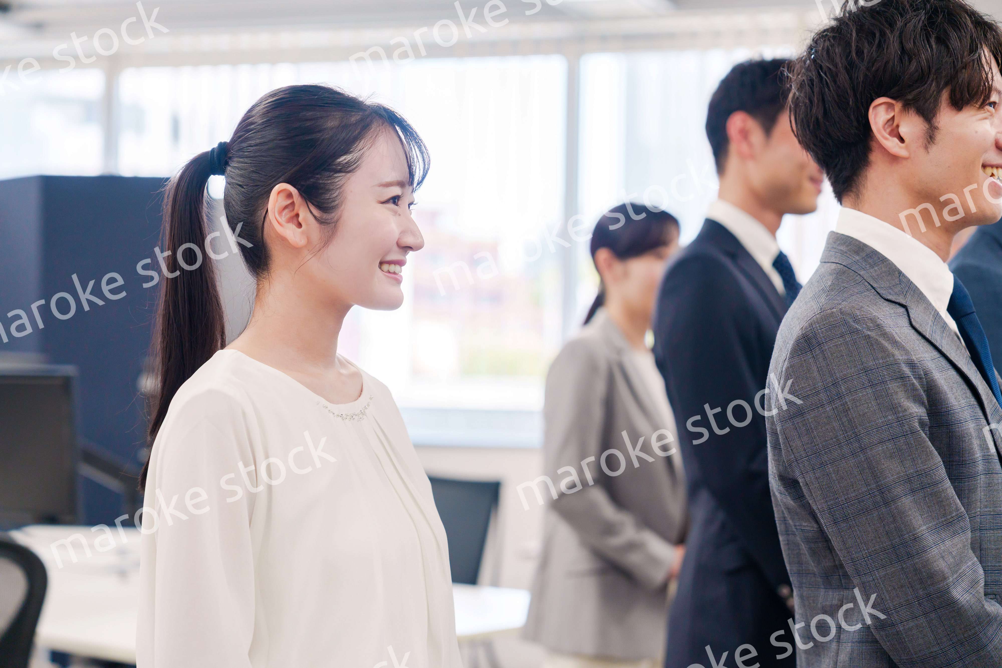 朝会で笑顔で話を聞くオフィスワーカー