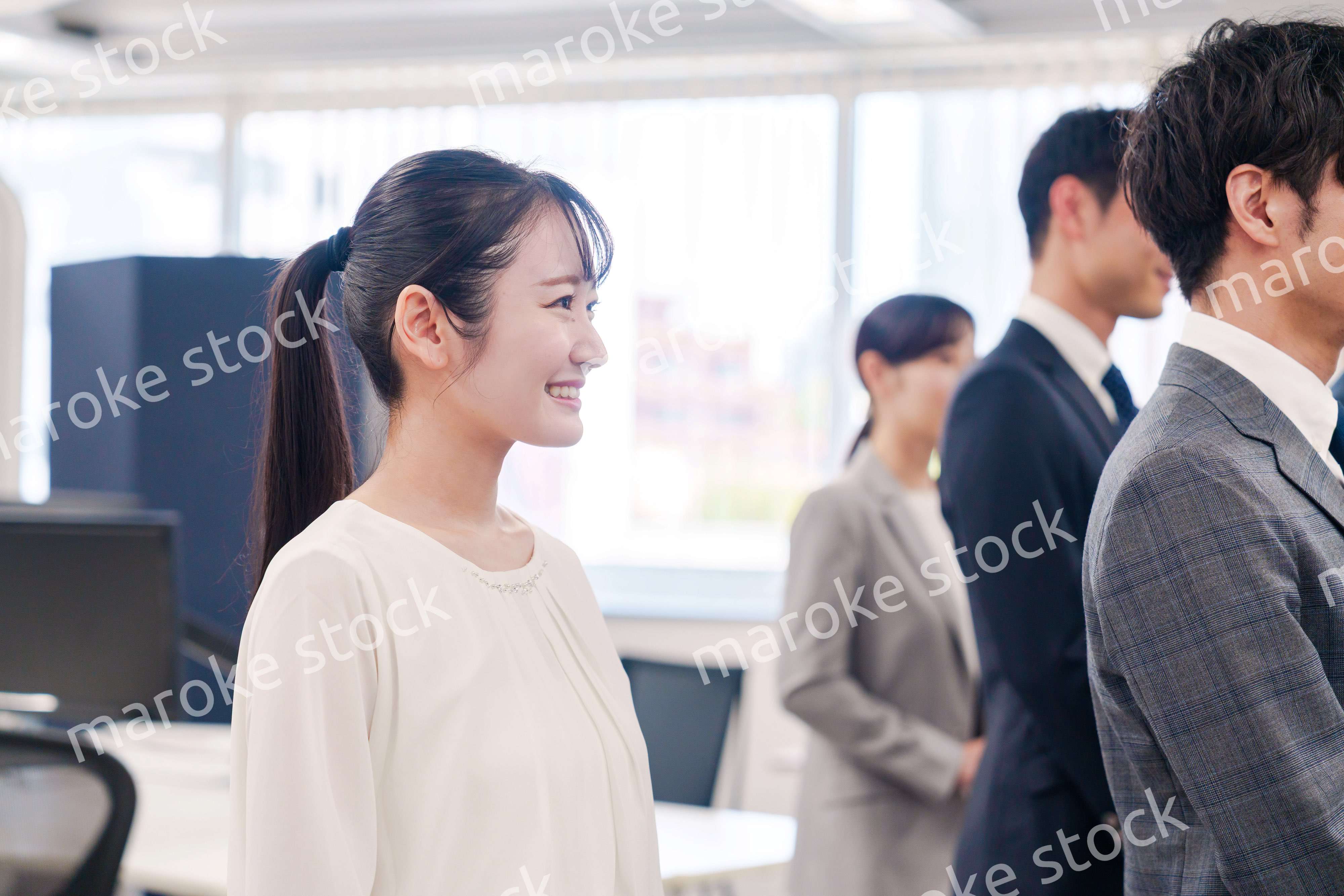 朝会で笑顔で話を聞くオフィスワーカー