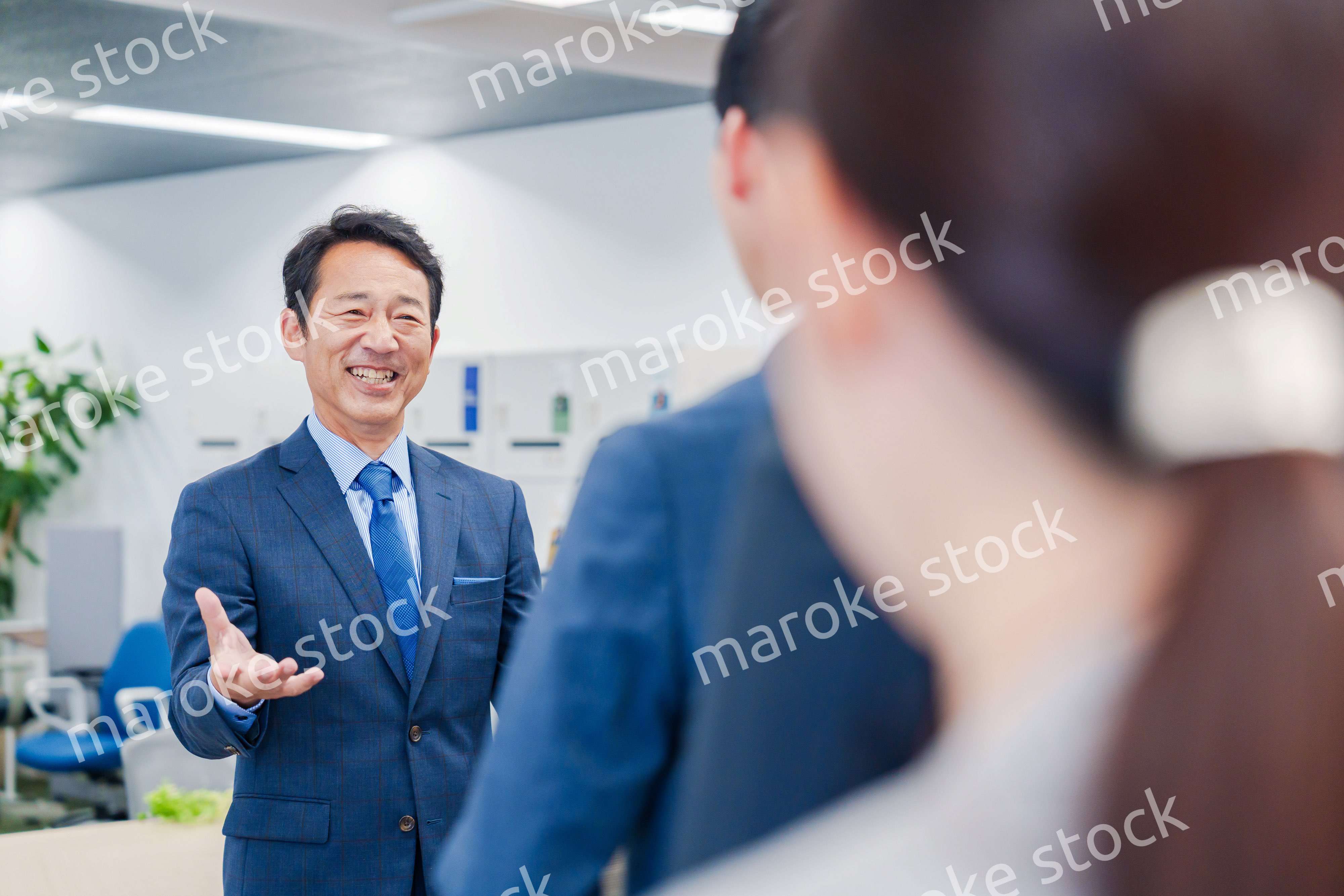 オフィスでの朝礼で挨拶をする管理職の男性