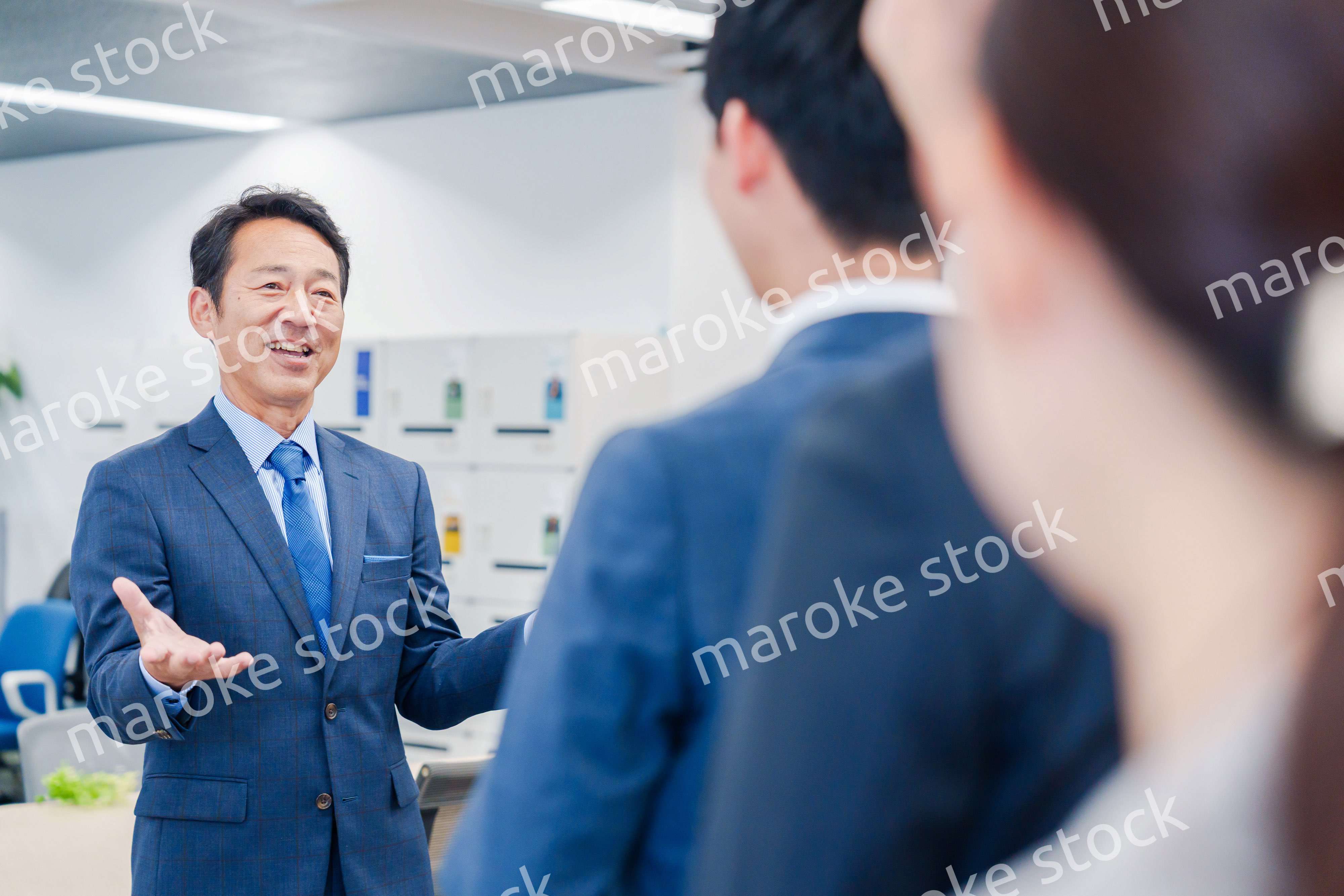 オフィスでの朝礼で挨拶をする管理職の男性
