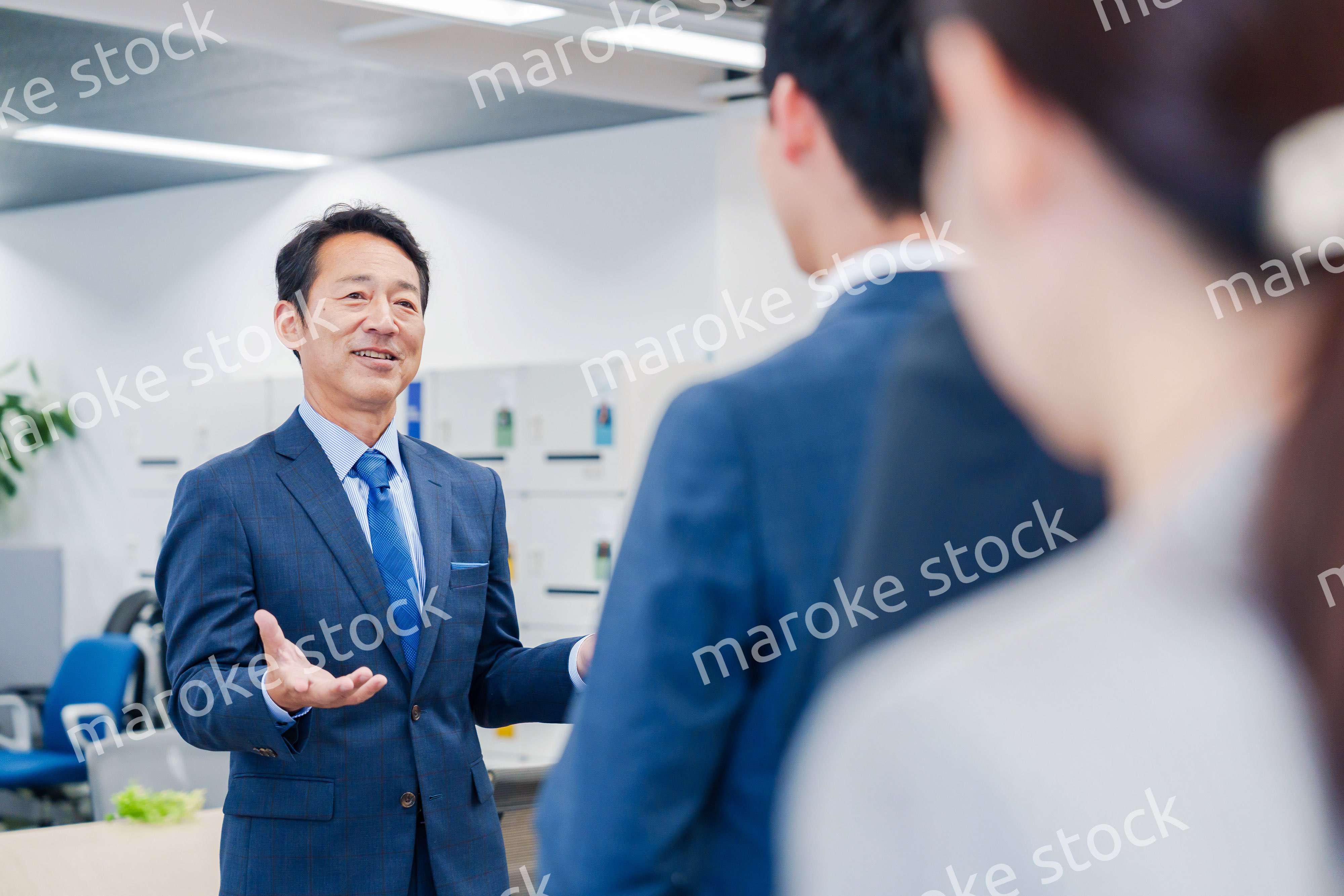 オフィスでの朝礼で挨拶をする管理職の男性