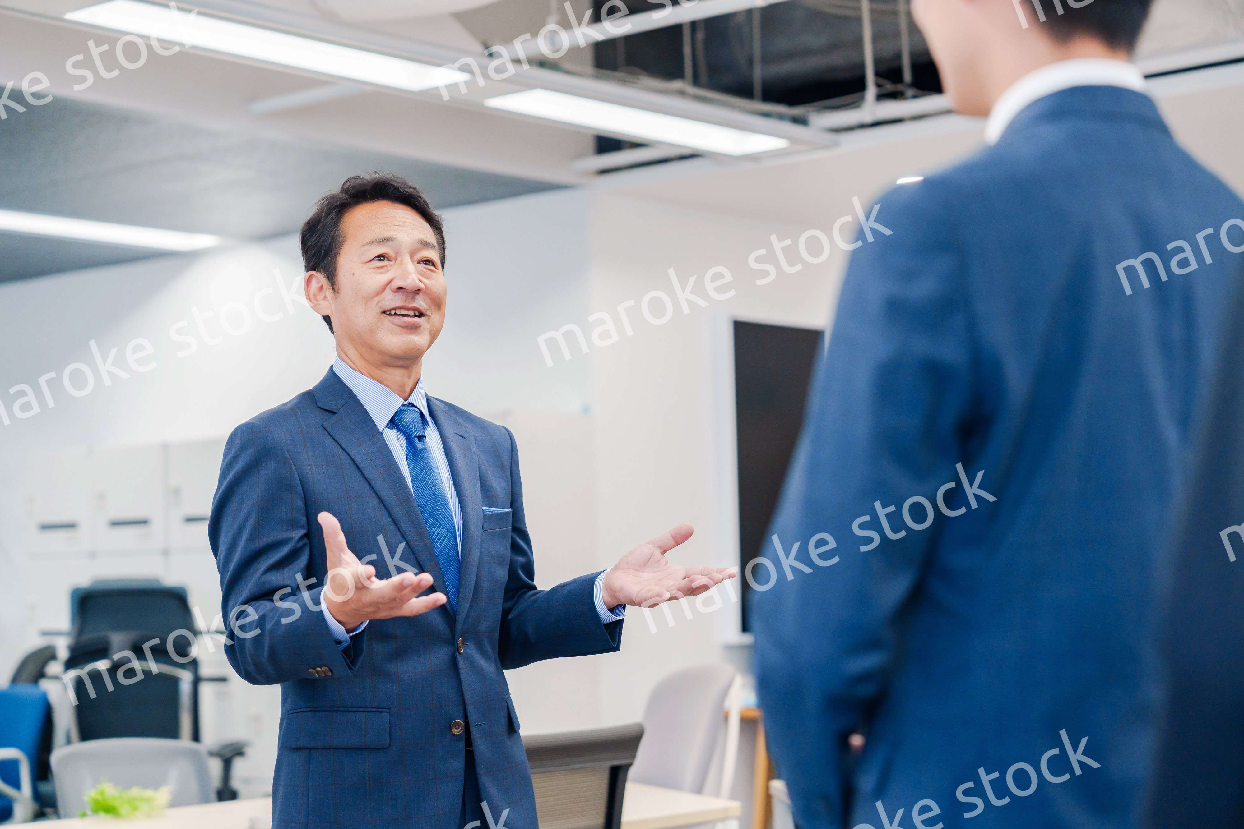 オフィスでの朝礼で挨拶をする管理職の男性