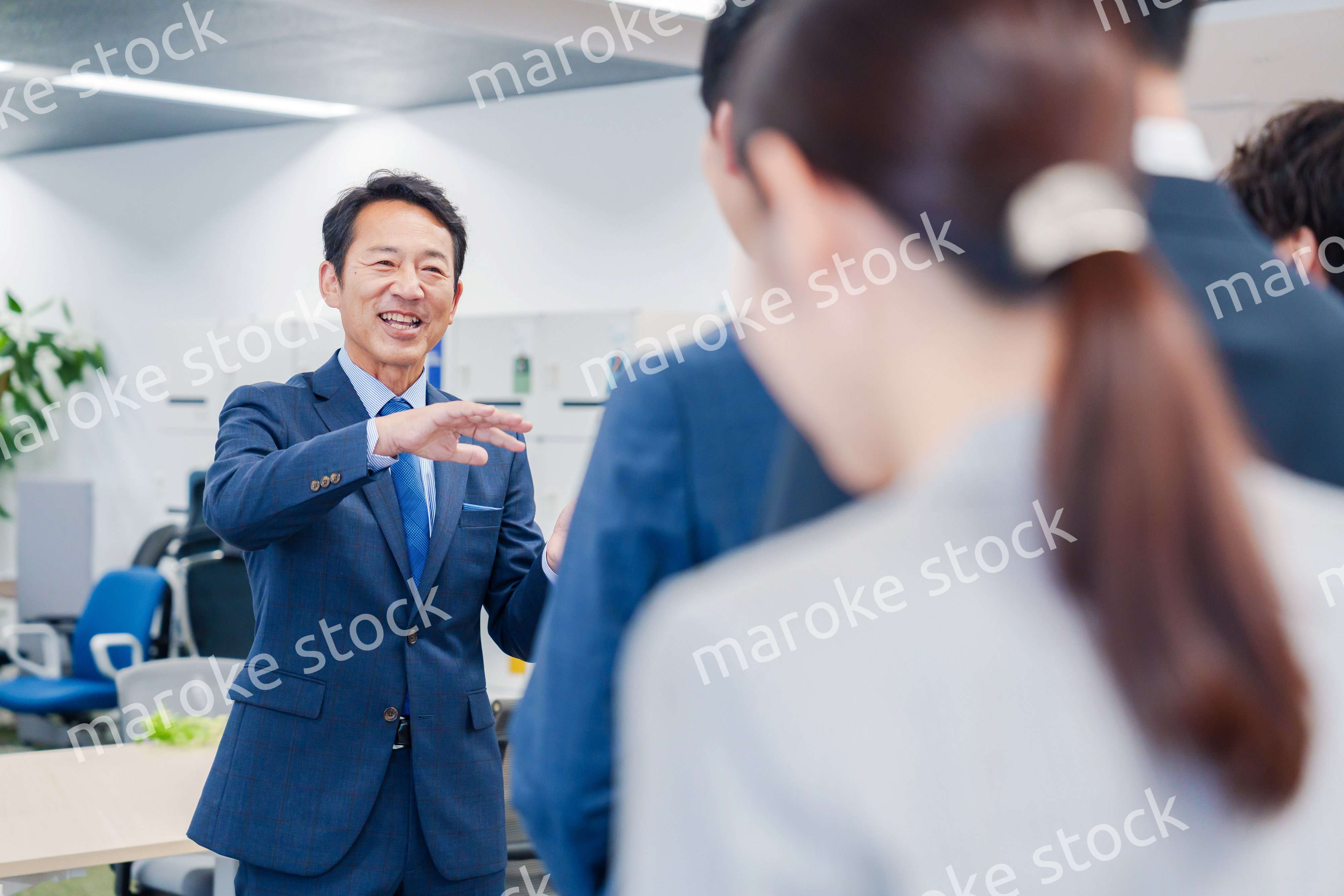 オフィスでの朝礼で挨拶をする管理職の男性