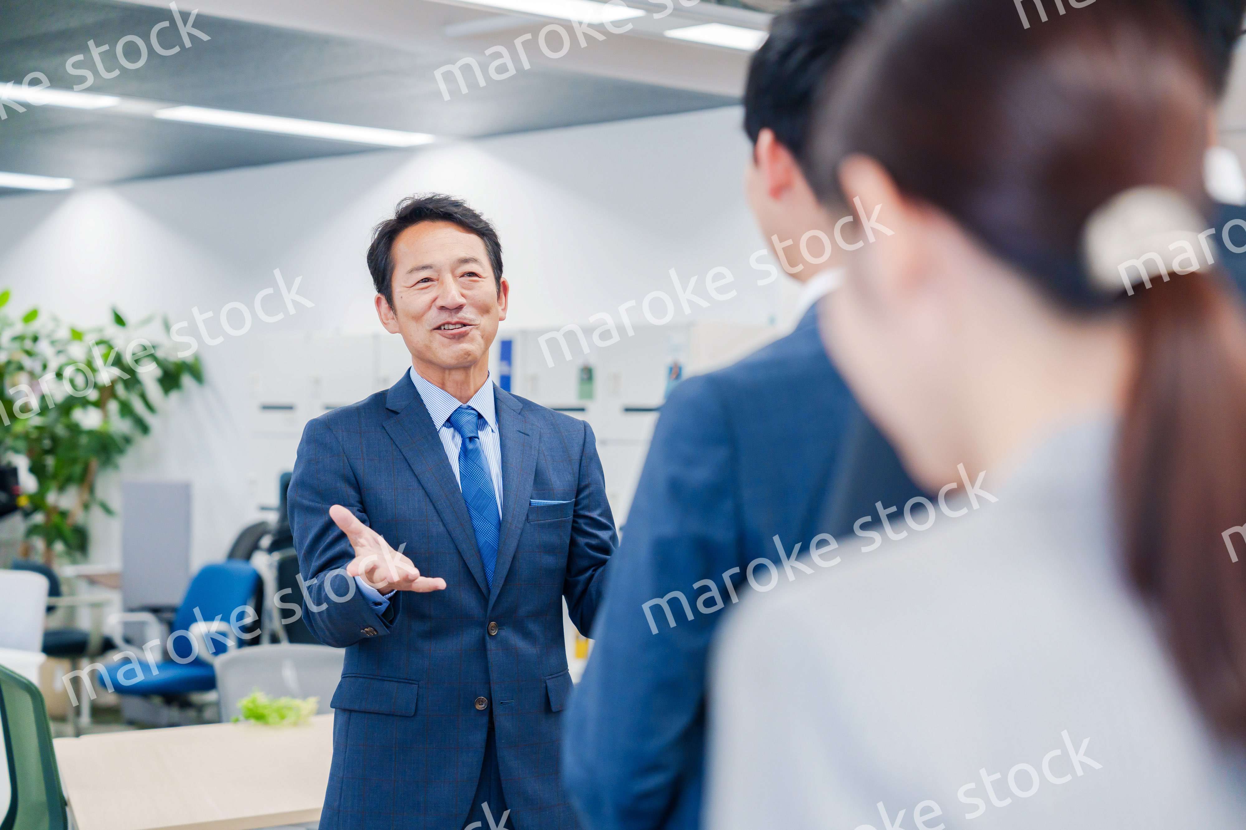 オフィスでの朝礼で挨拶をする管理職の男性