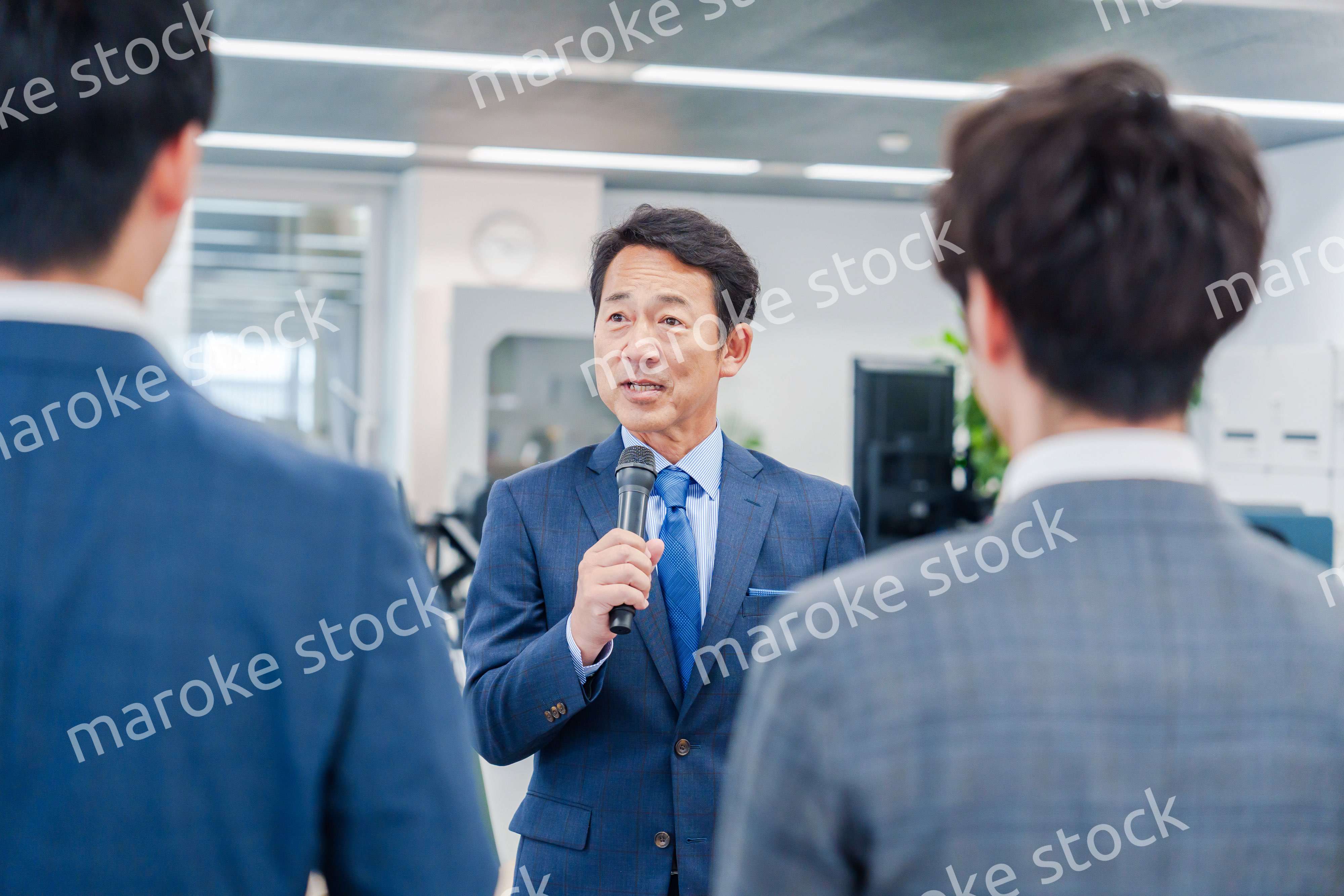 オフィスでの朝礼で挨拶をする管理職の男性