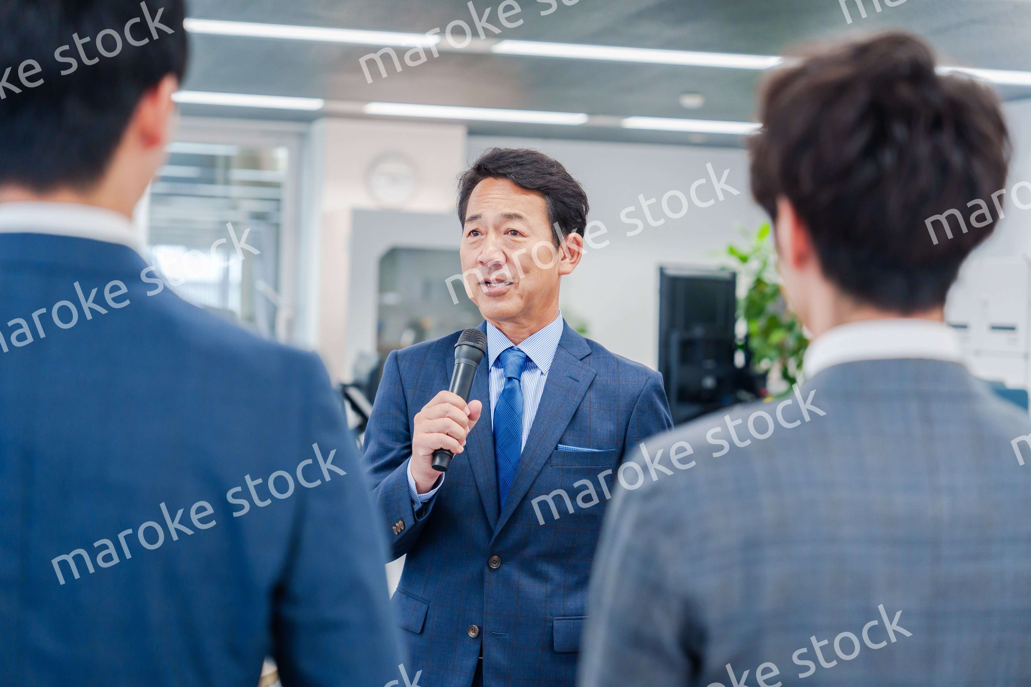 オフィスでの朝礼で挨拶をする管理職の男性