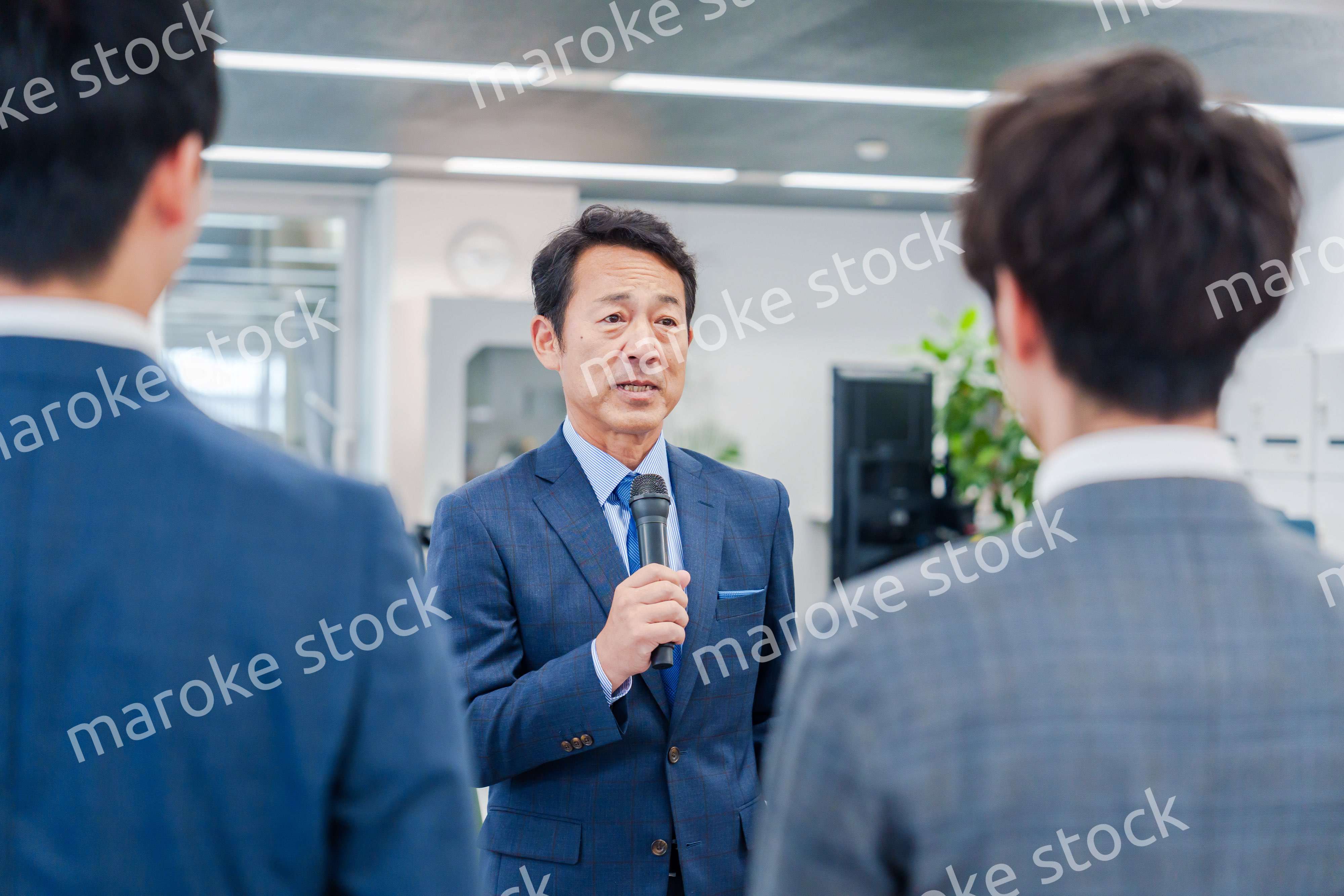オフィスでの朝礼で挨拶をする管理職の男性