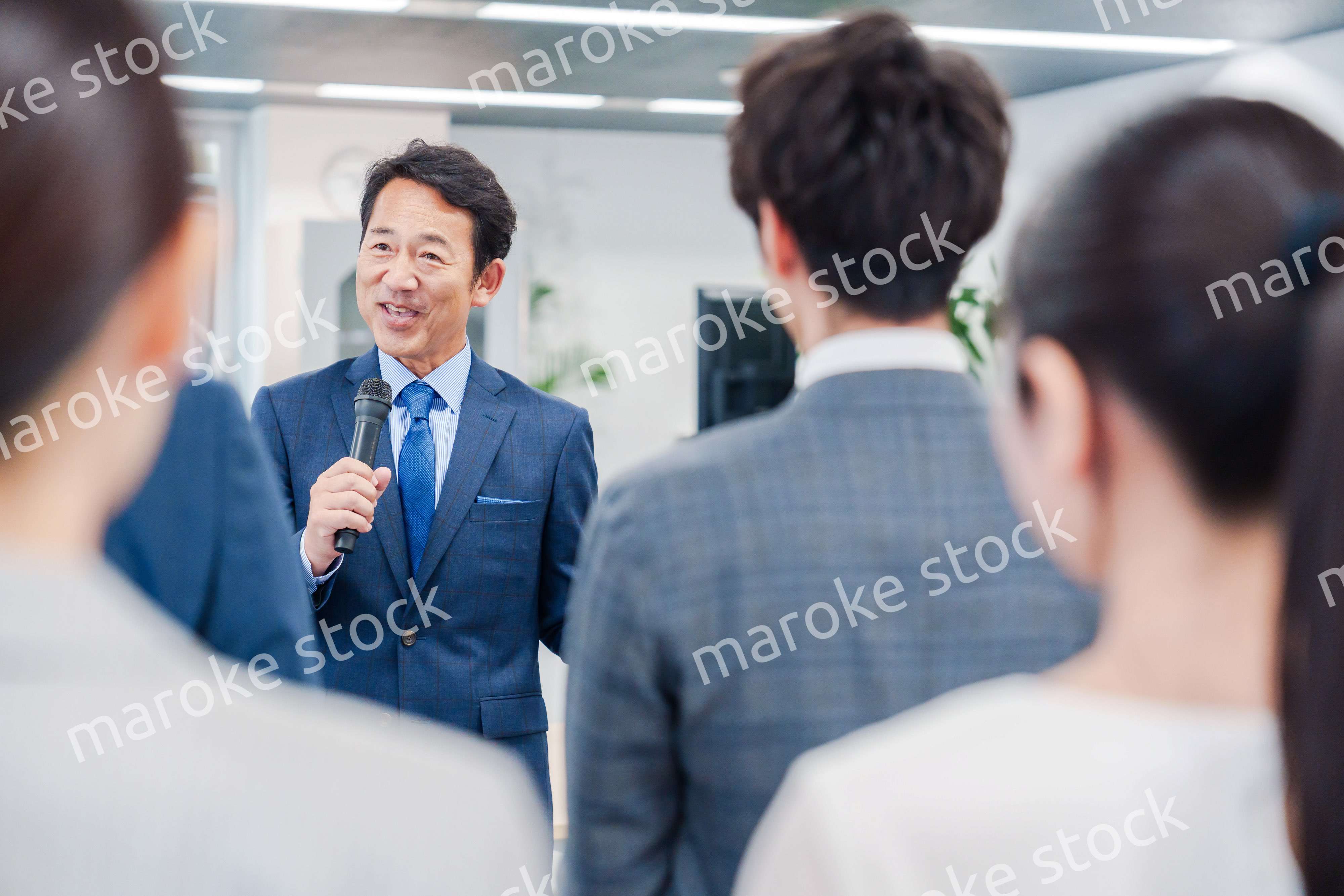 オフィスでの朝礼で挨拶をする管理職の男性