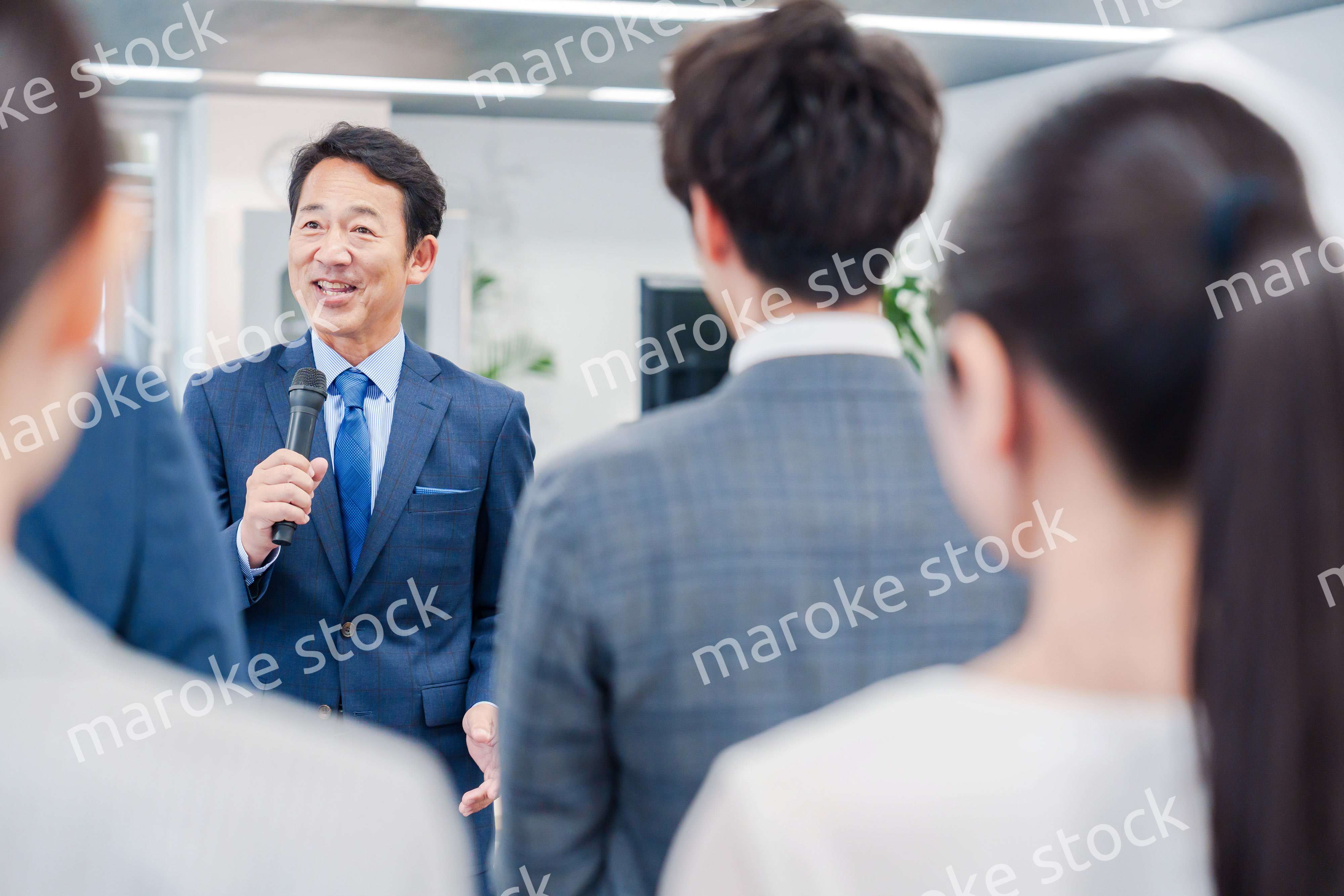 オフィスでの朝礼で挨拶をする管理職の男性