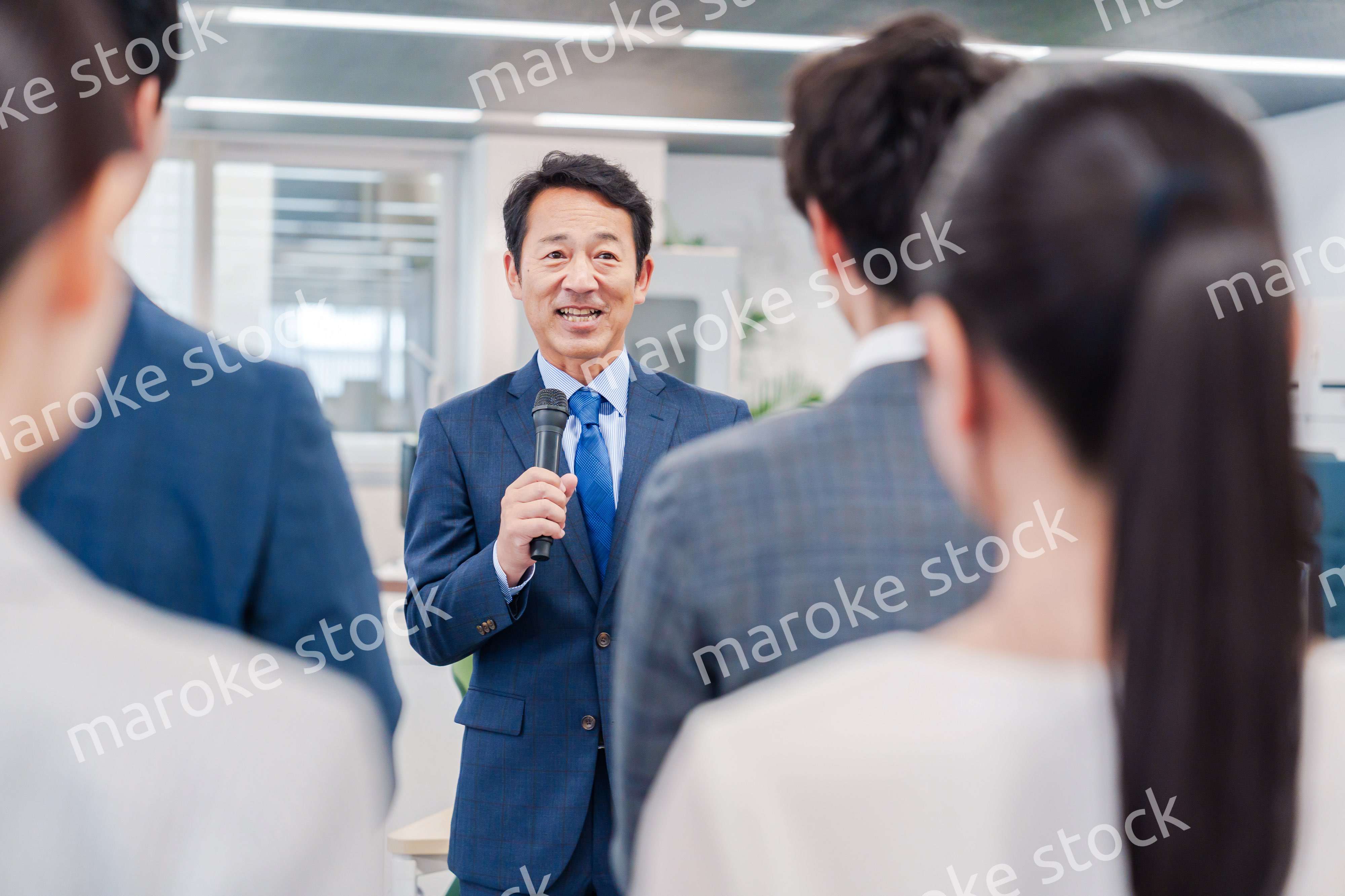 オフィスでの朝礼で挨拶をする管理職の男性