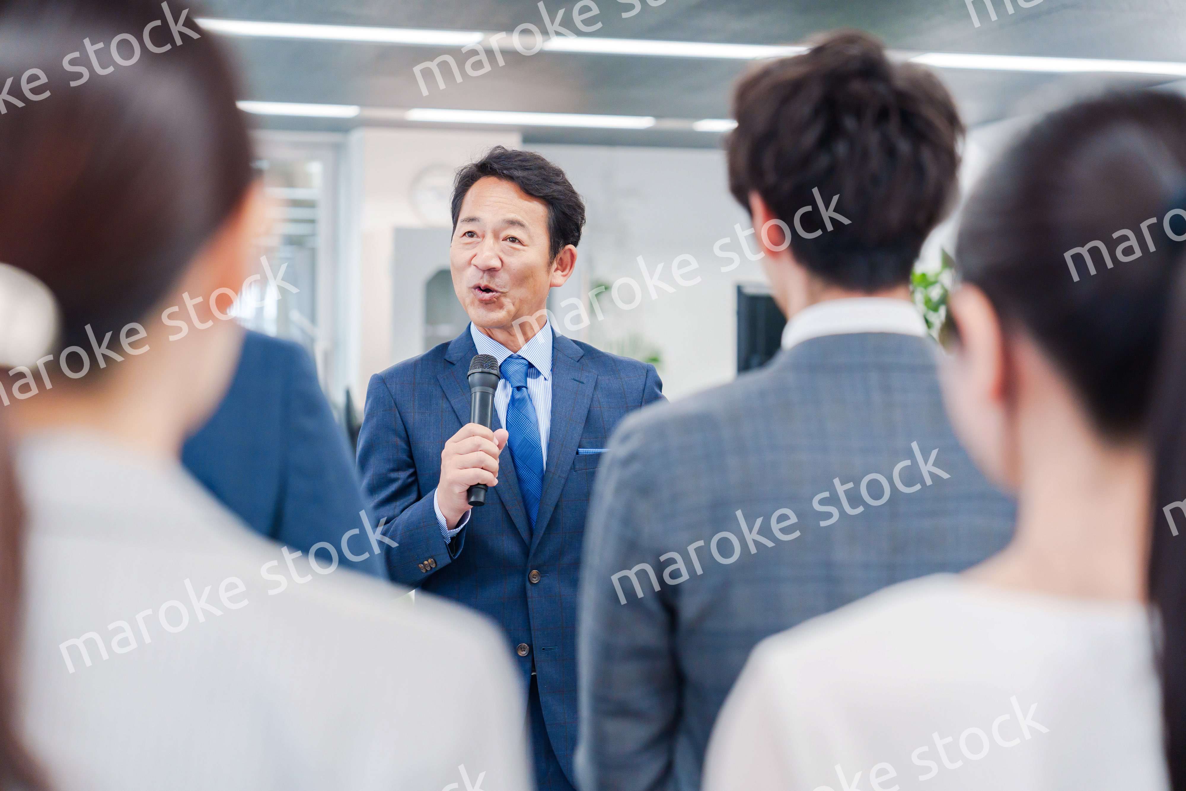 オフィスでの朝礼で挨拶をする管理職の男性