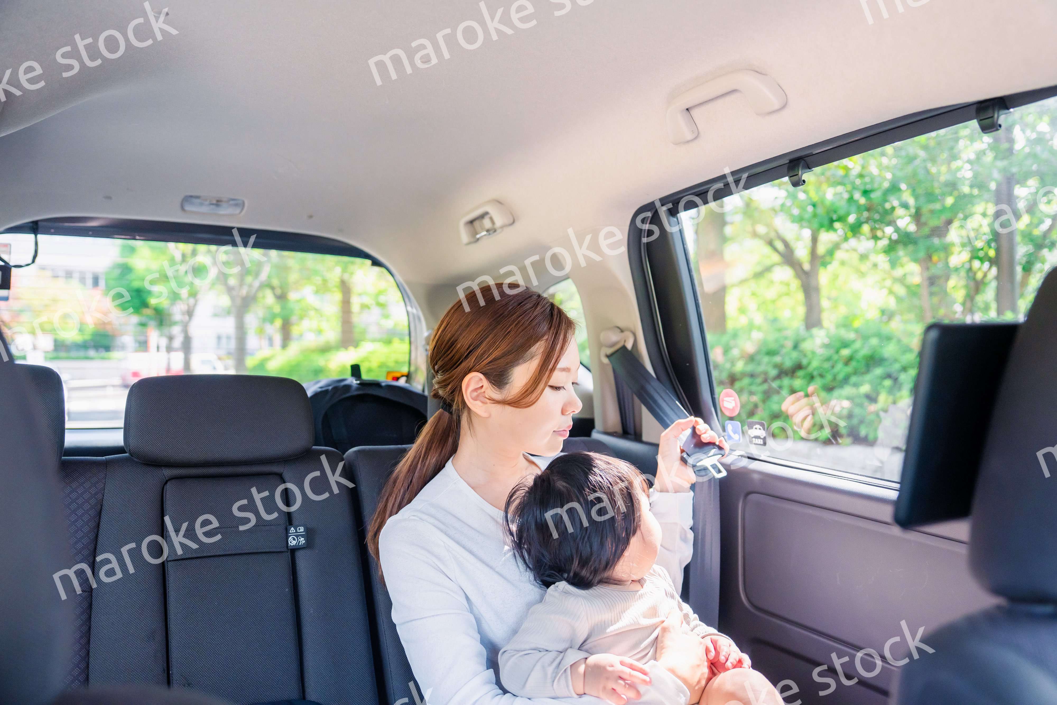 タクシーでシートベルトをする子連れのお母さん