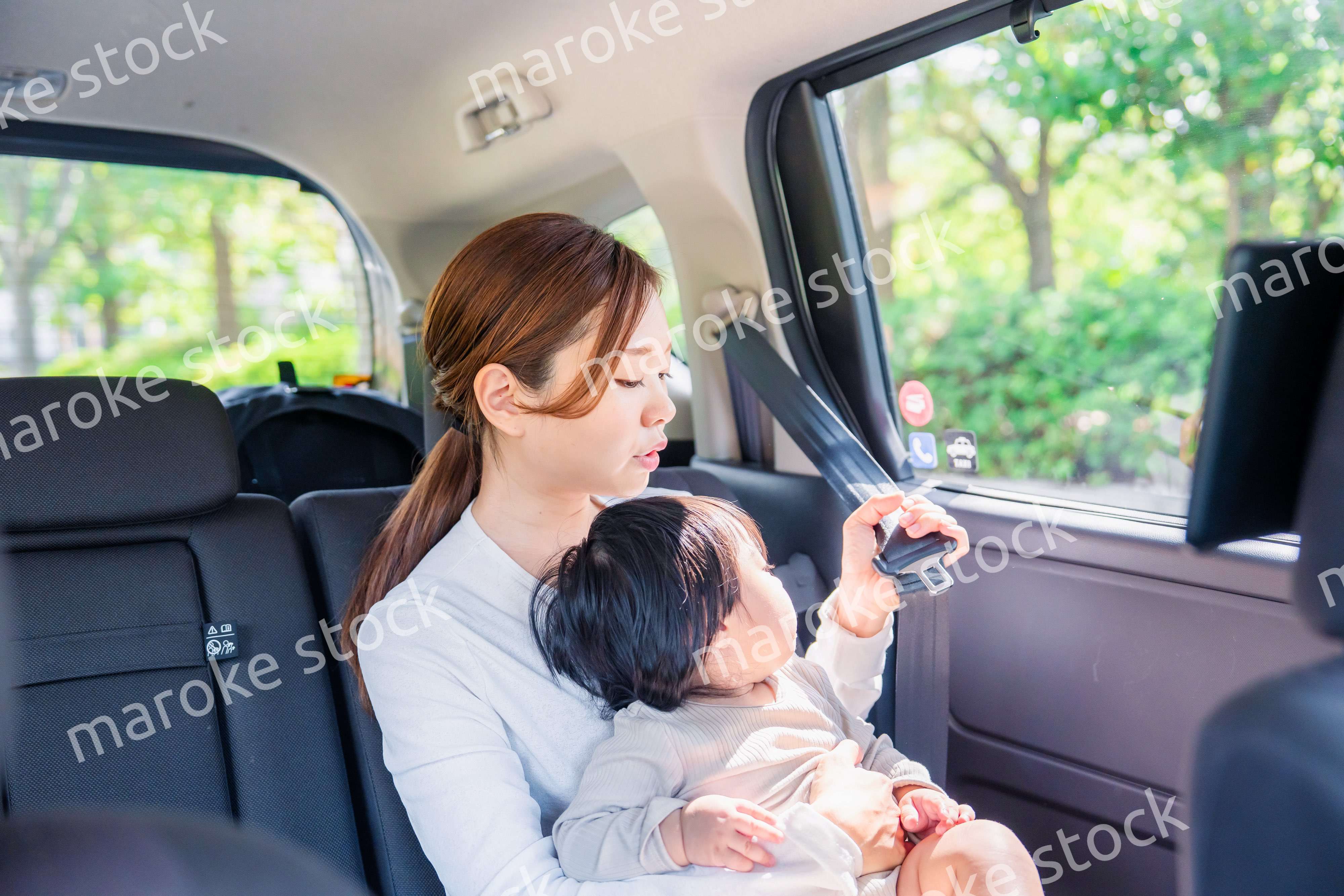 タクシーでシートベルトをする子連れのお母さん