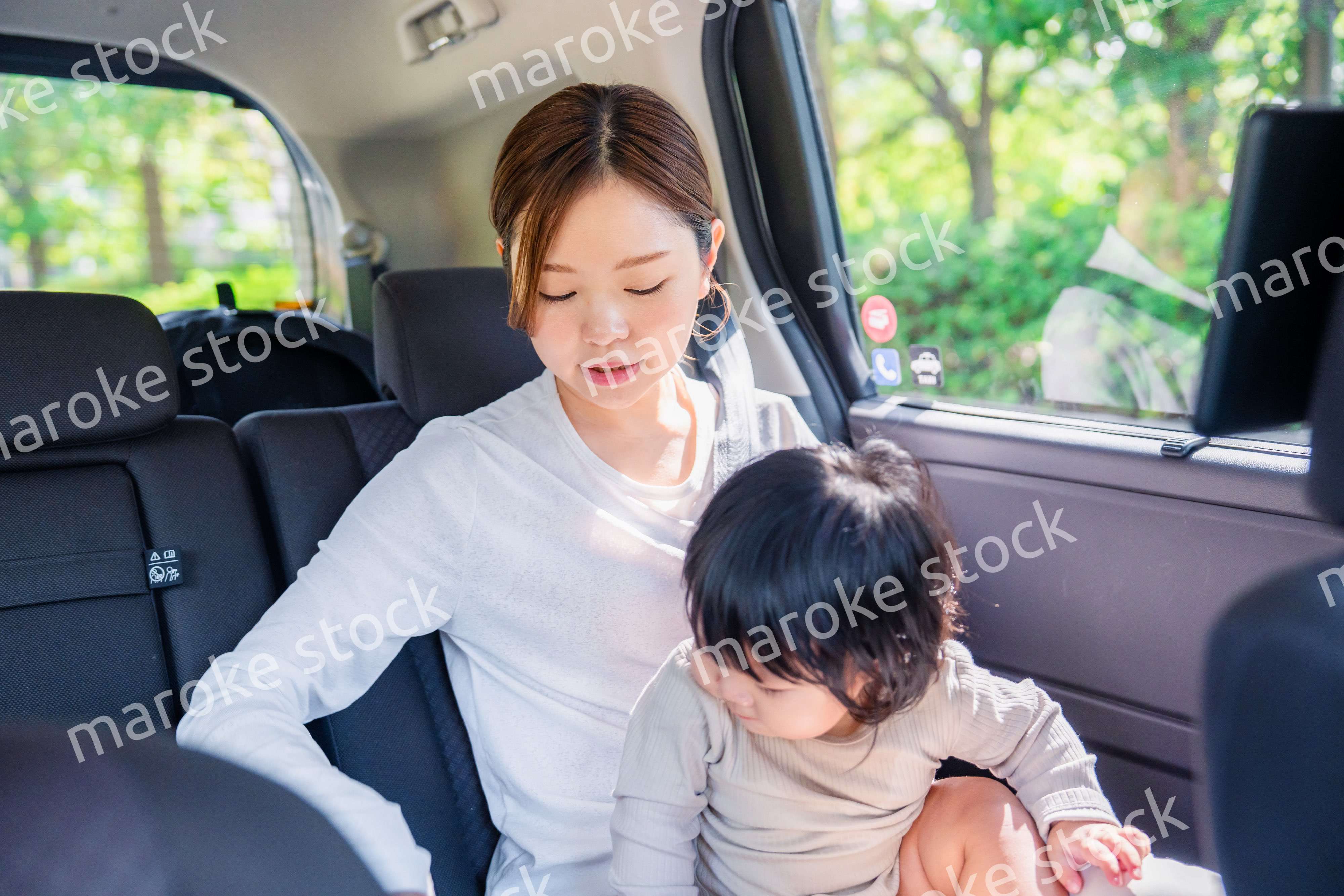 タクシーでシートベルトをする子連れのお母さん