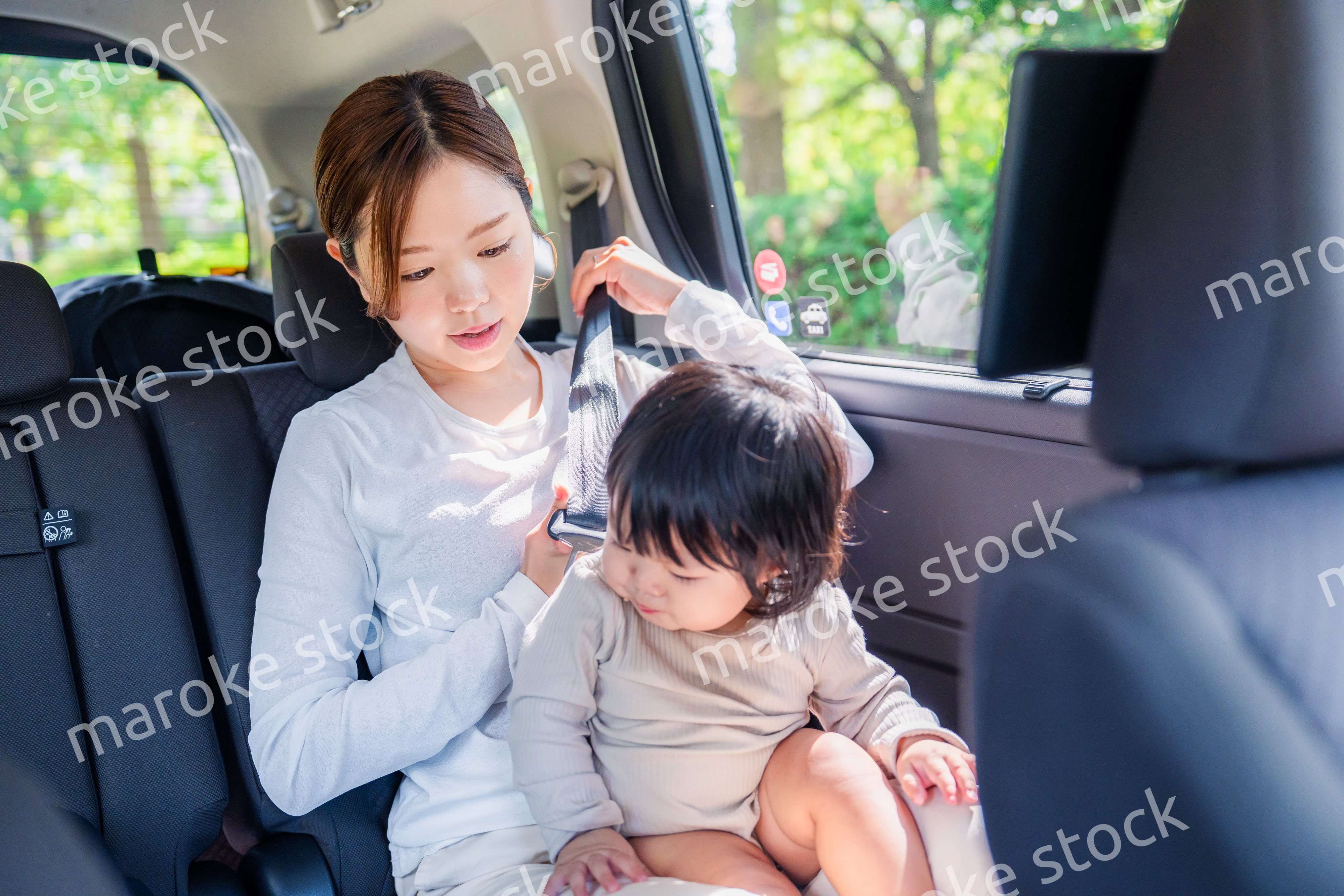 タクシーでシートベルトをする子連れのお母さん