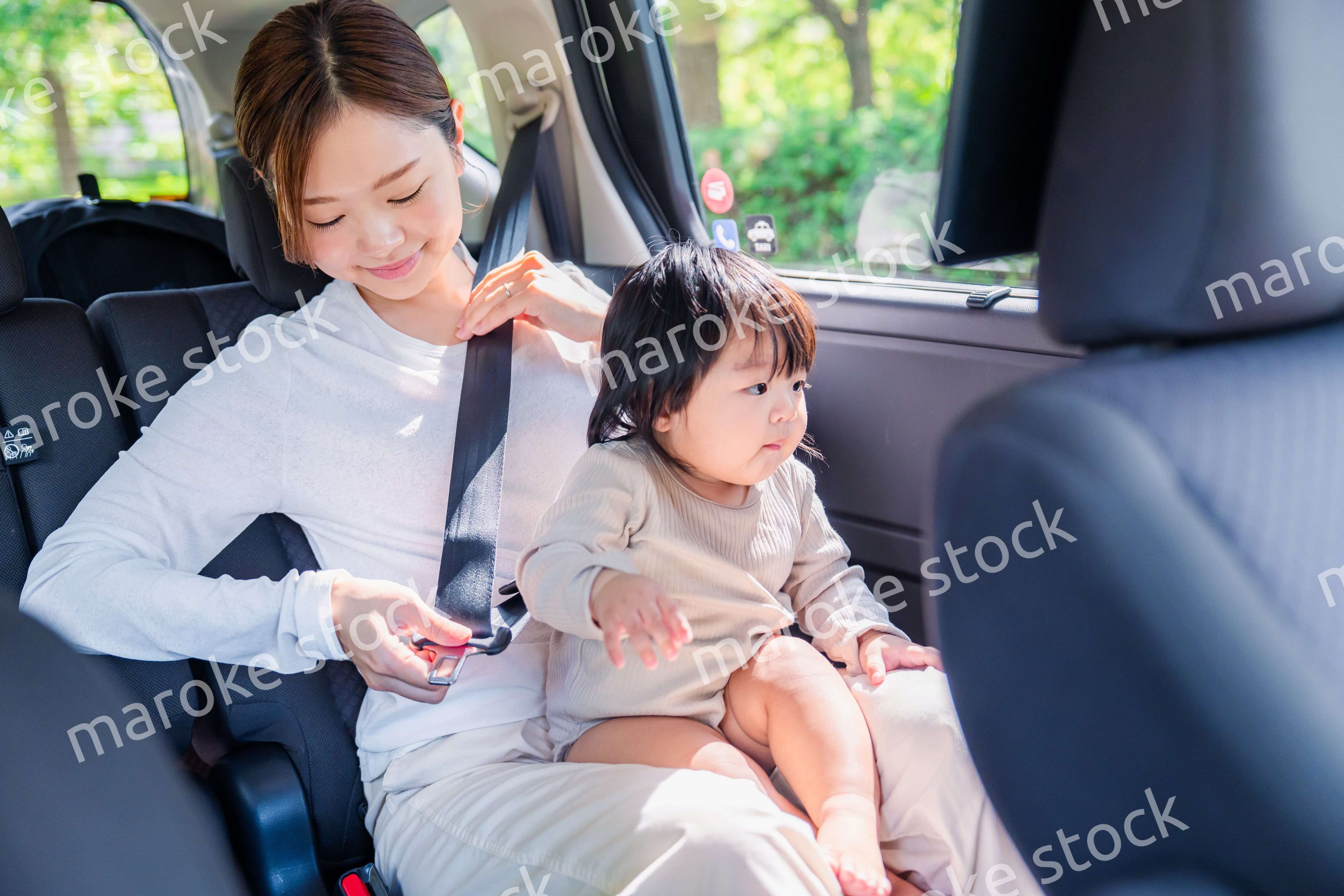 タクシーでシートベルトをする子連れのお母さん