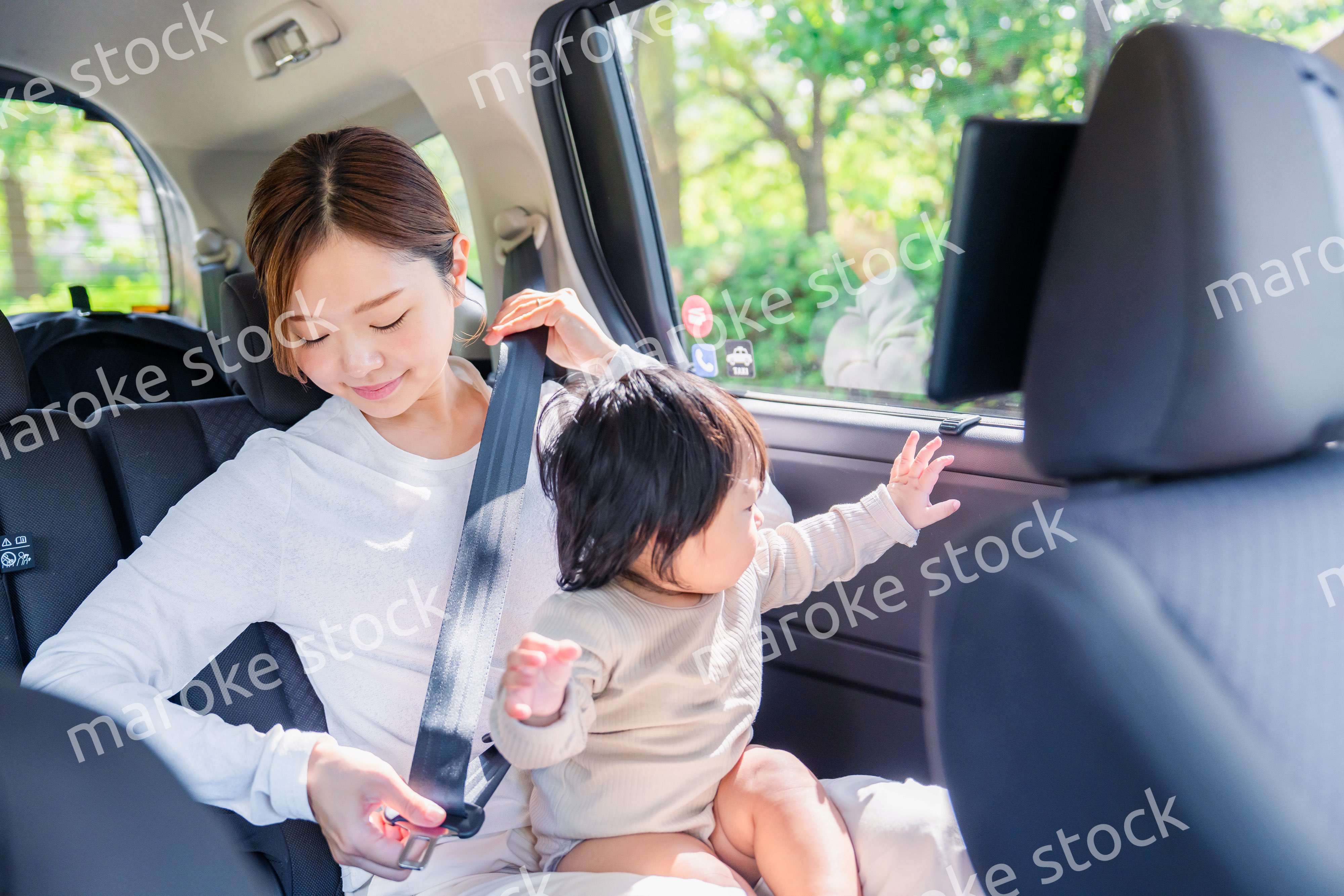 タクシーでシートベルトをする子連れのお母さん