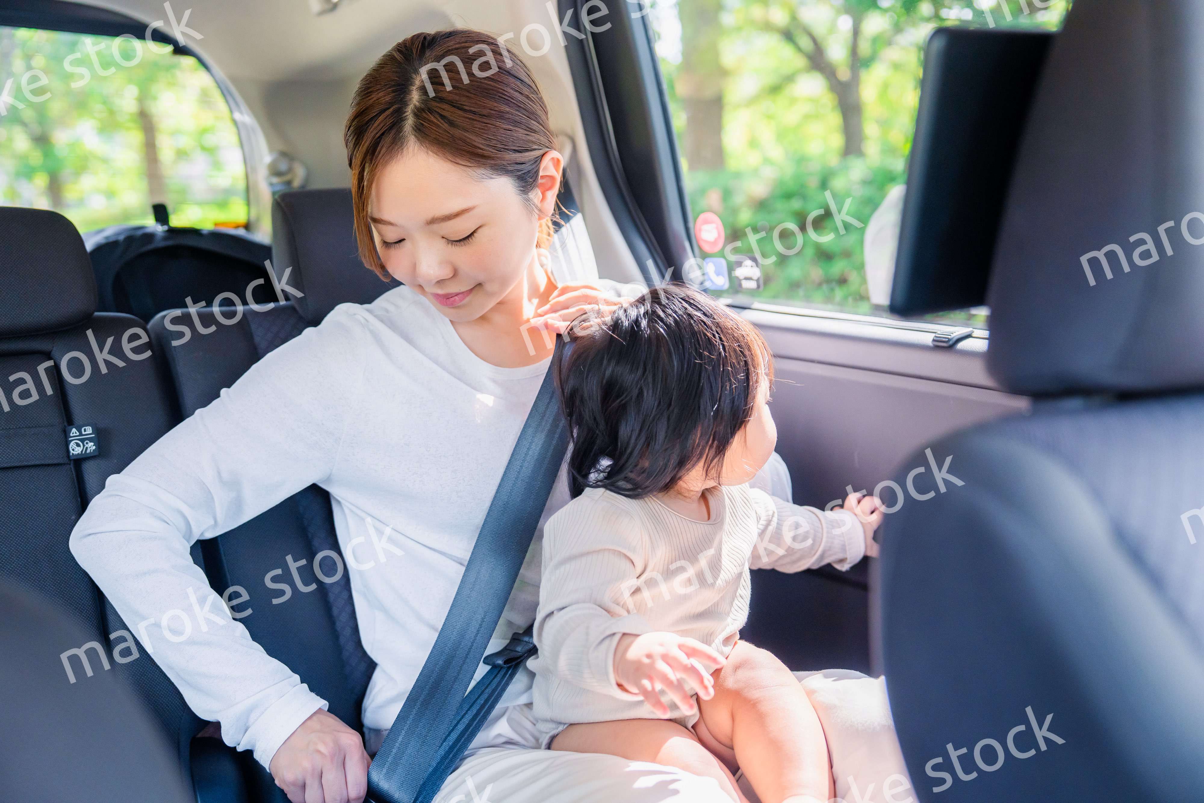 タクシーでシートベルトをする子連れのお母さん