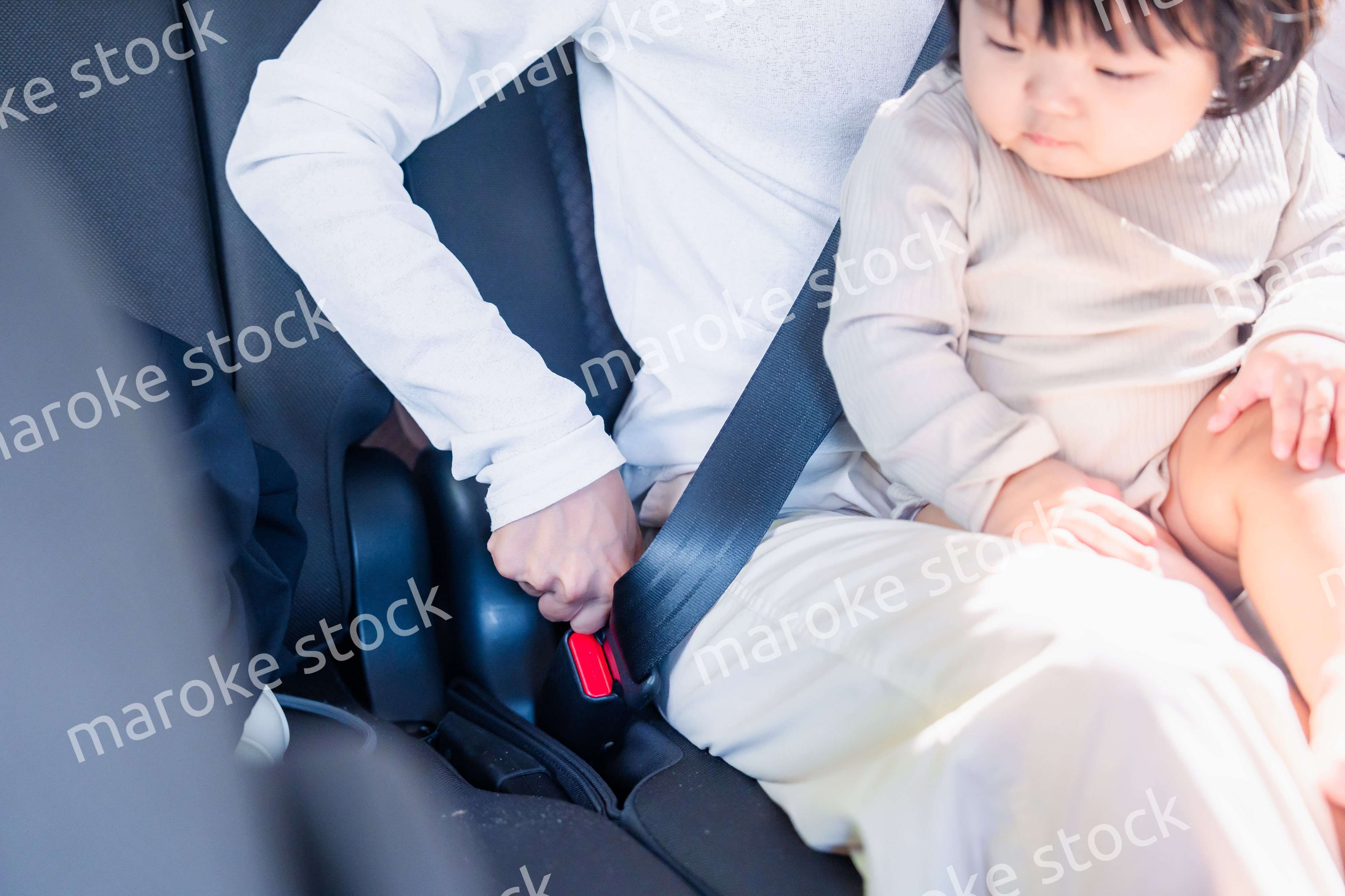 タクシーでシートベルトをする子連れのお母さん