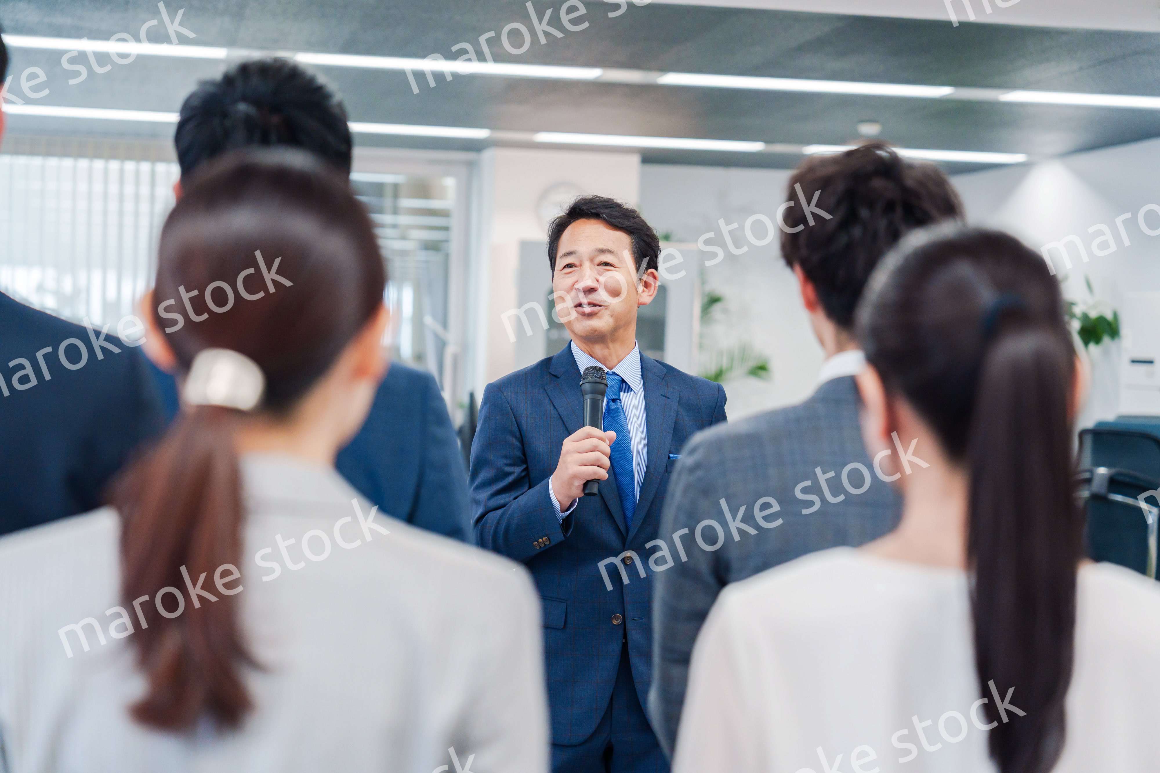 オフィスでの朝礼で挨拶をする管理職の男性