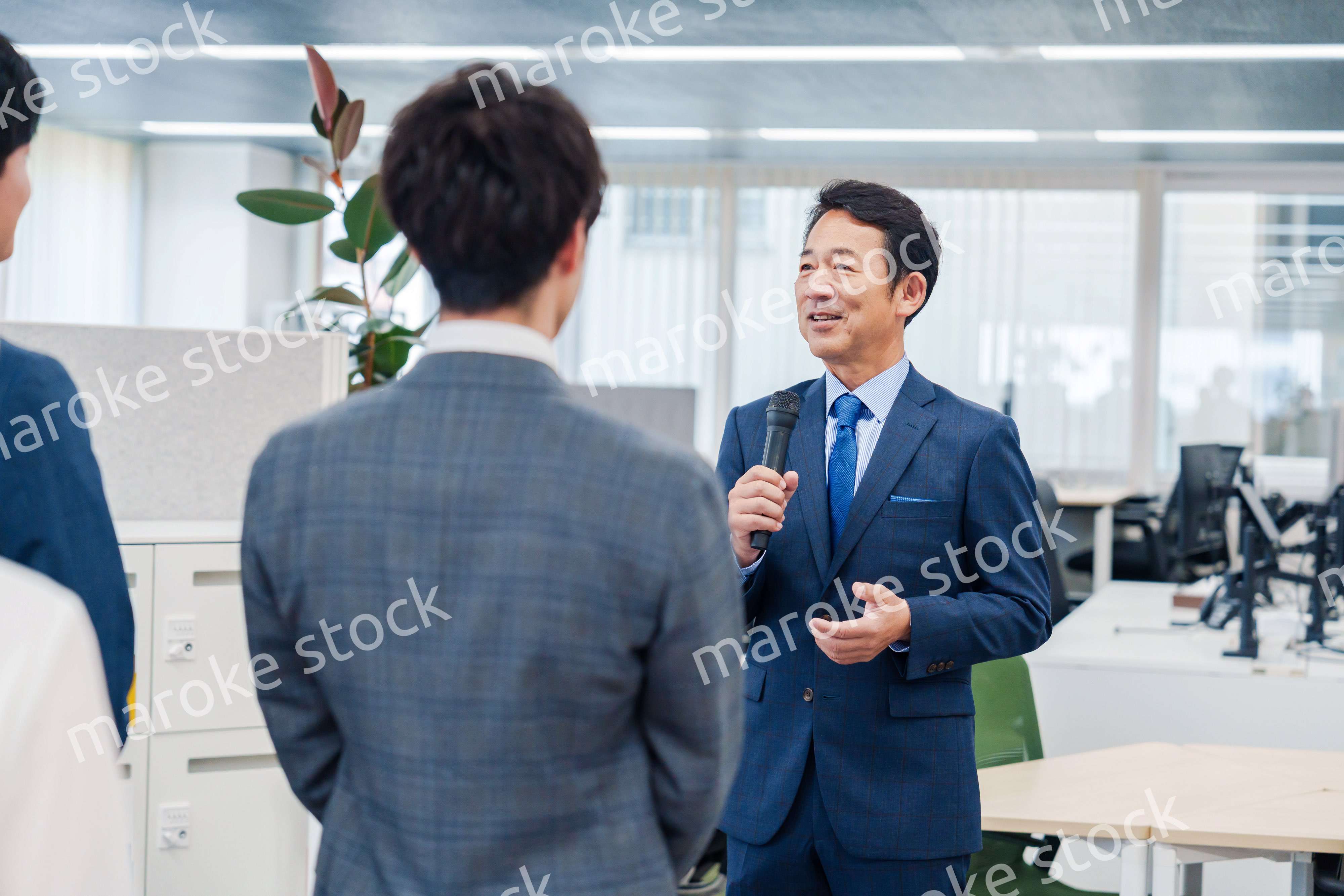 オフィスでの朝礼で挨拶をする管理職の男性