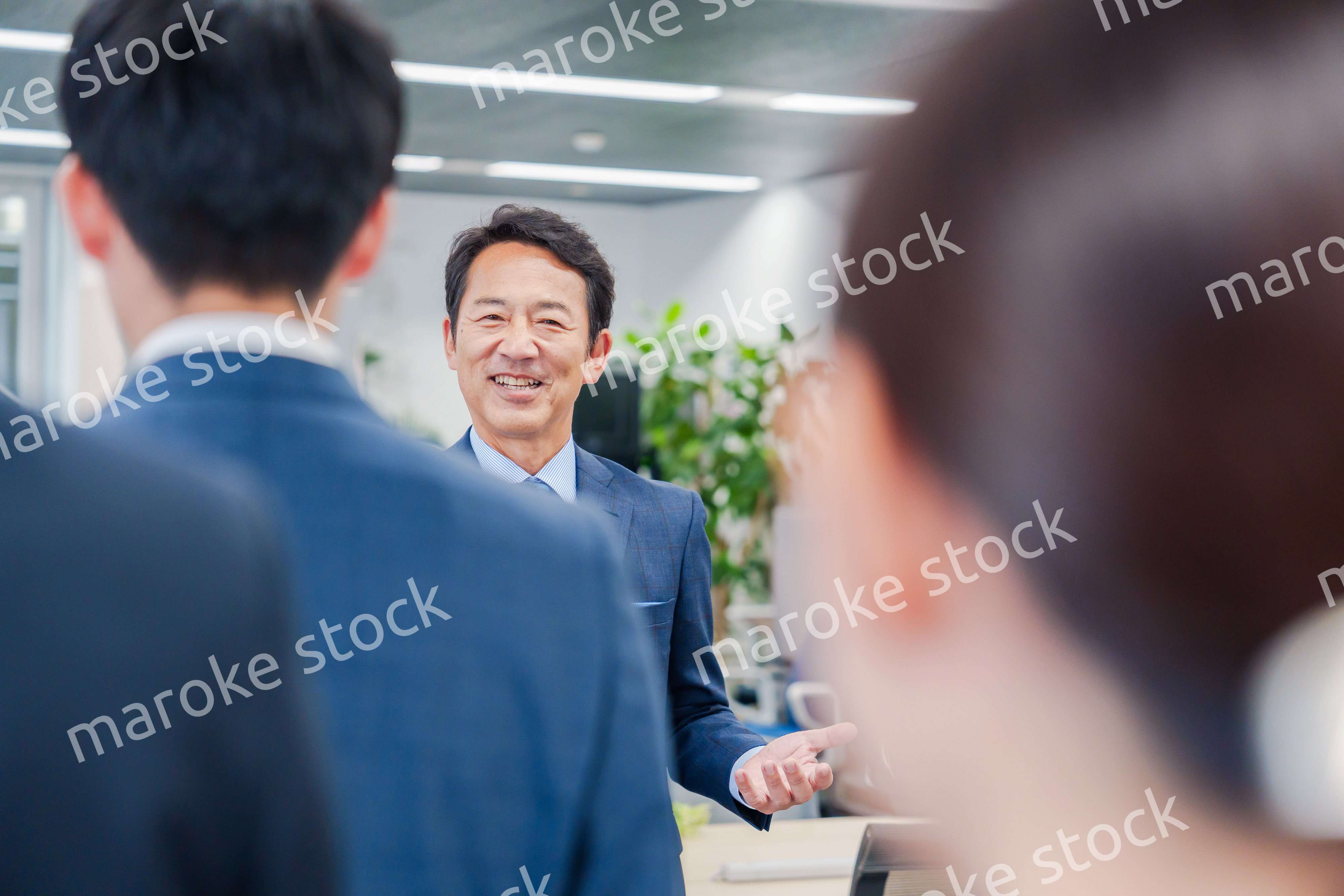 オフィスでの朝礼で挨拶をする管理職の男性