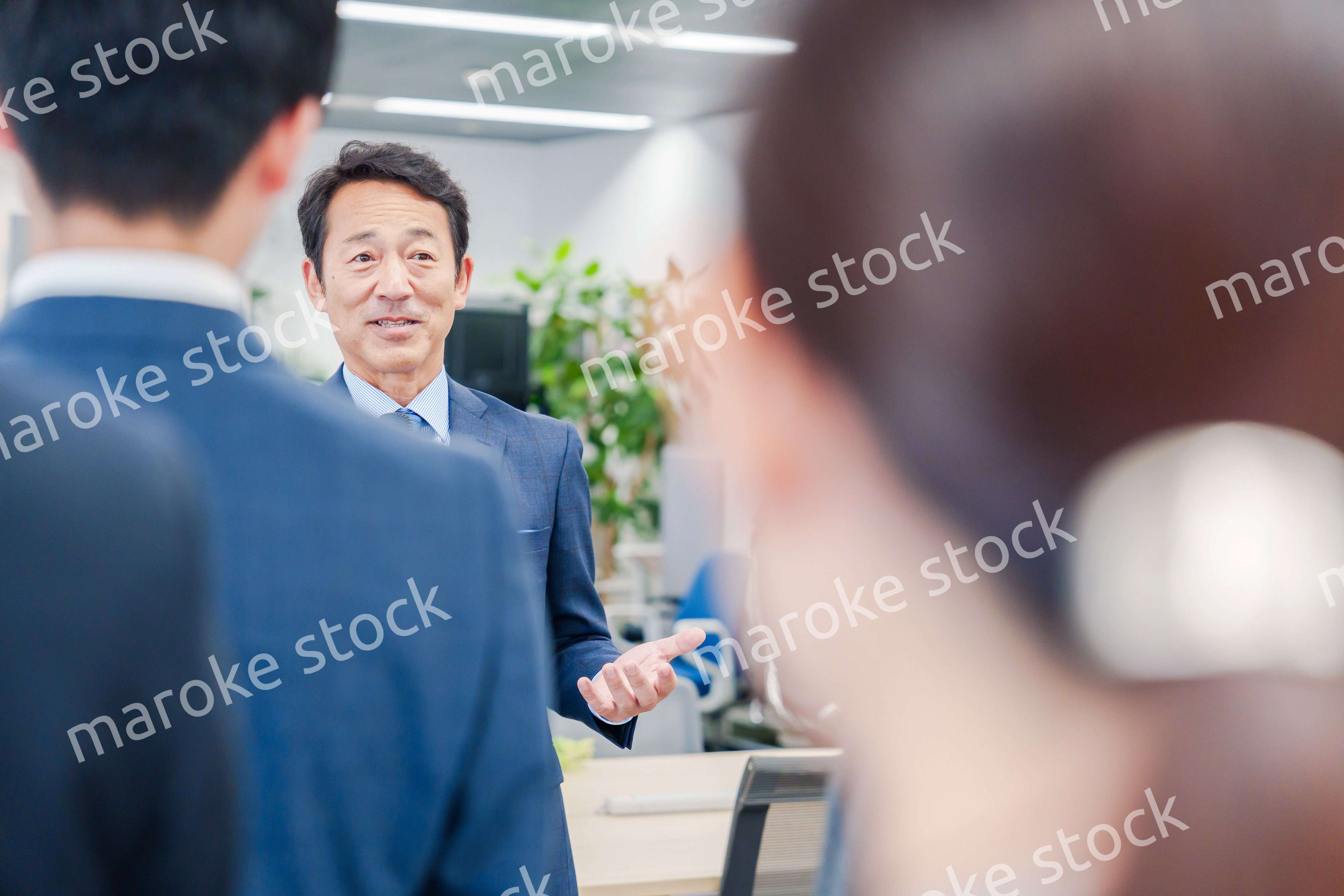 オフィスでの朝礼で挨拶をする管理職の男性