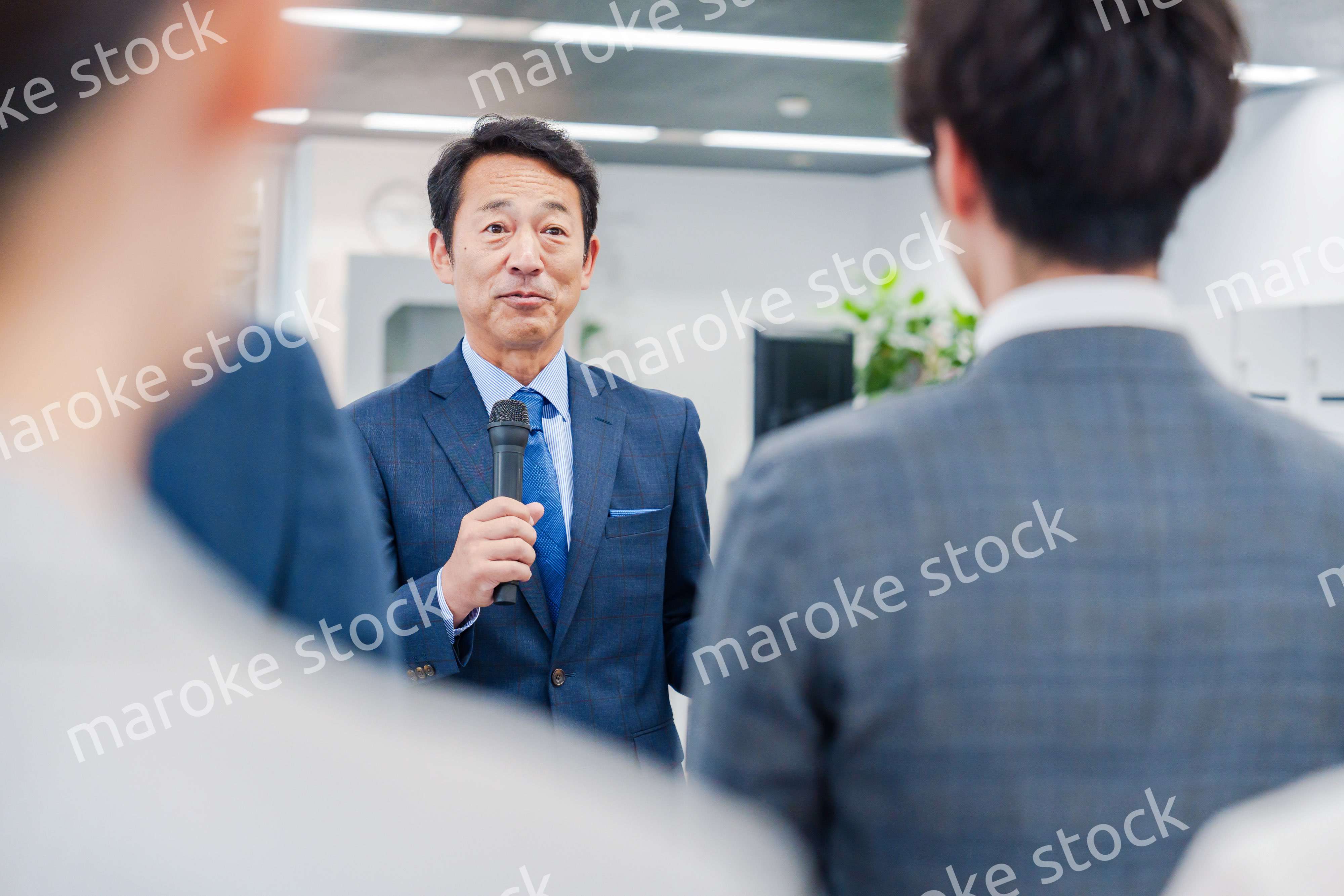 オフィスでの朝礼で挨拶をする管理職の男性
