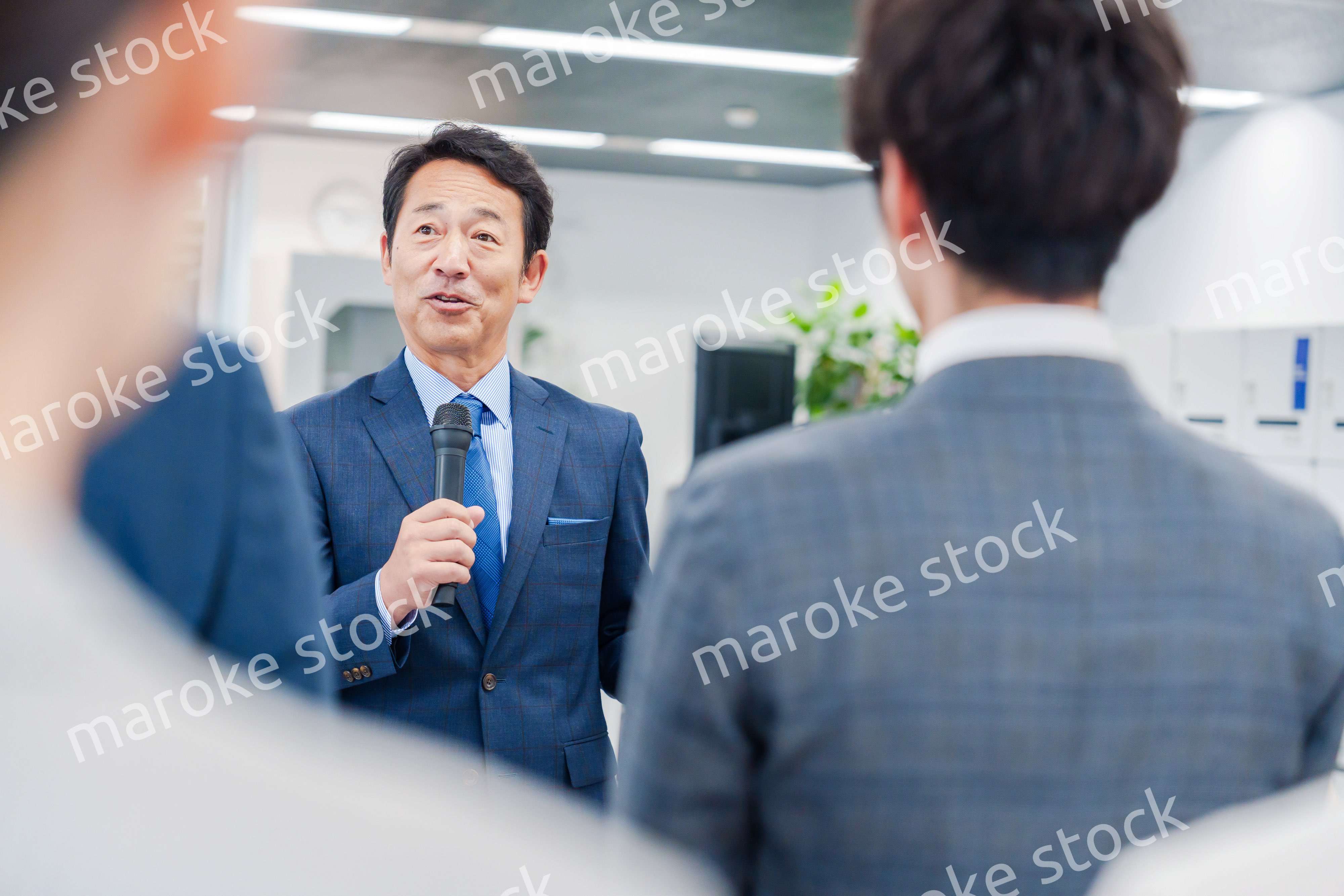 オフィスでの朝礼で挨拶をする管理職の男性