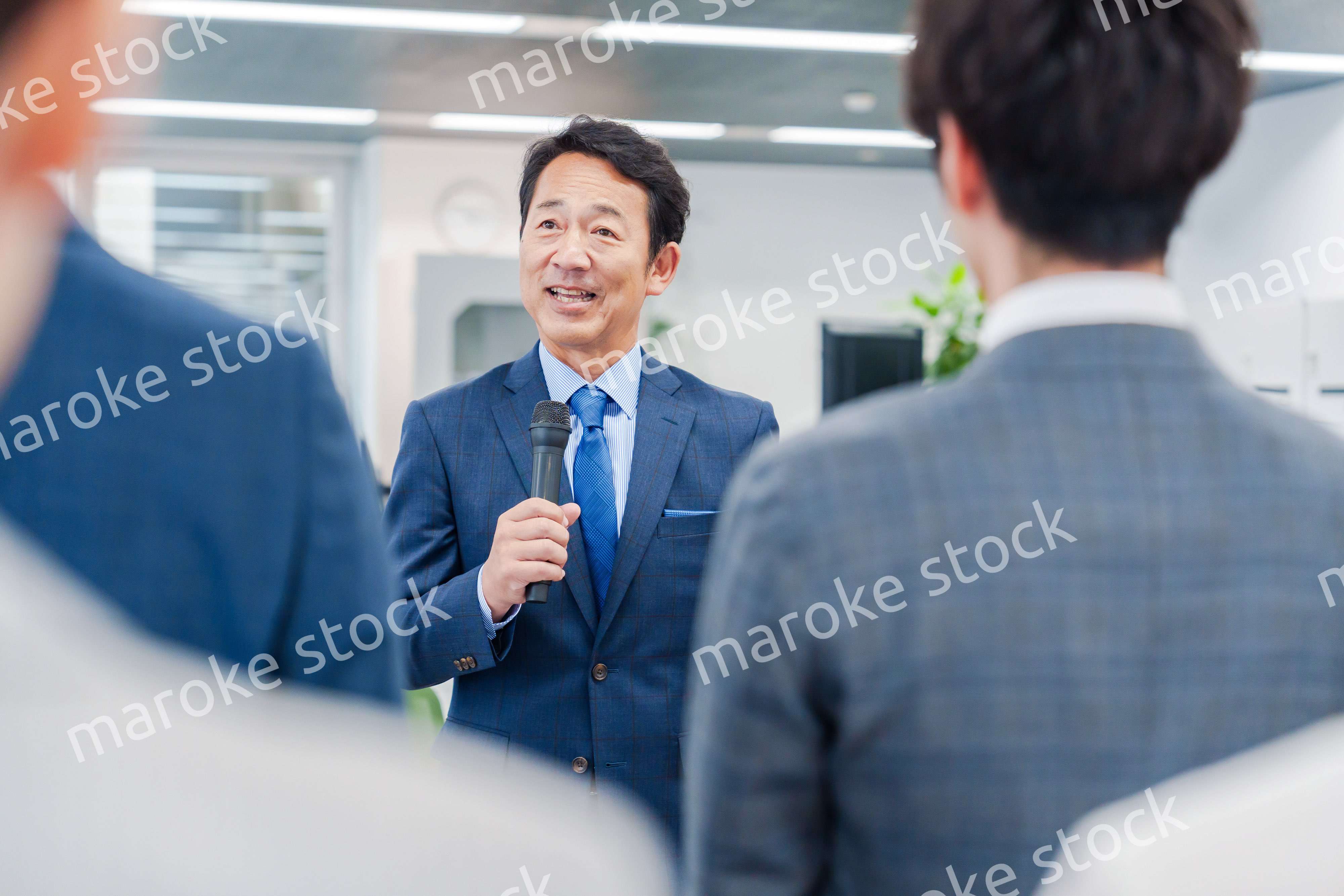 オフィスでの朝礼で挨拶をする管理職の男性
