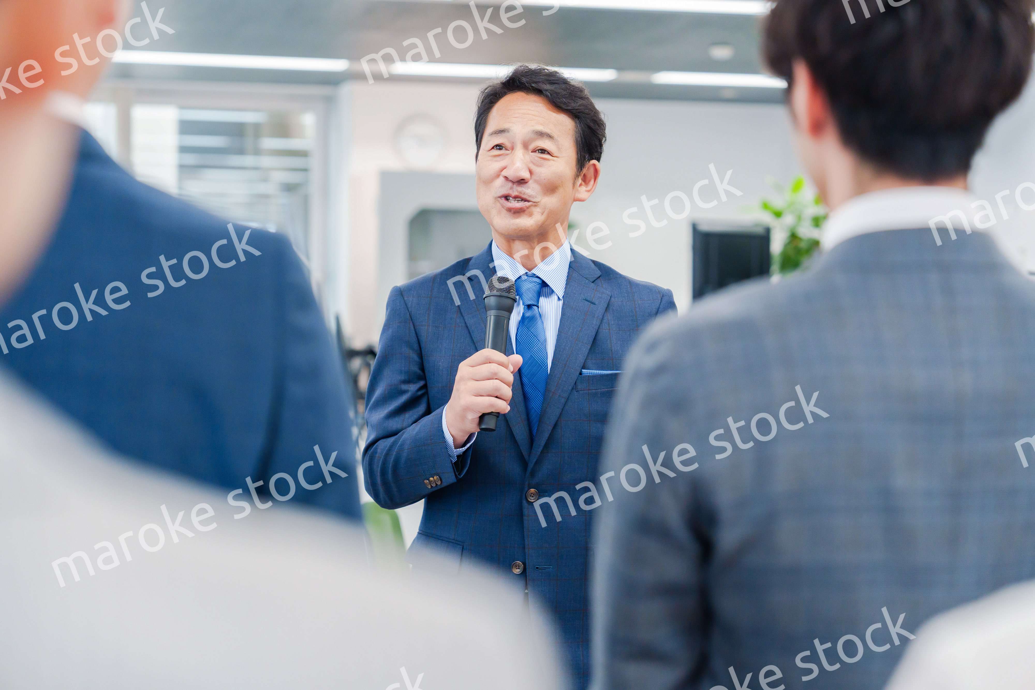 オフィスでの朝礼で挨拶をする管理職の男性