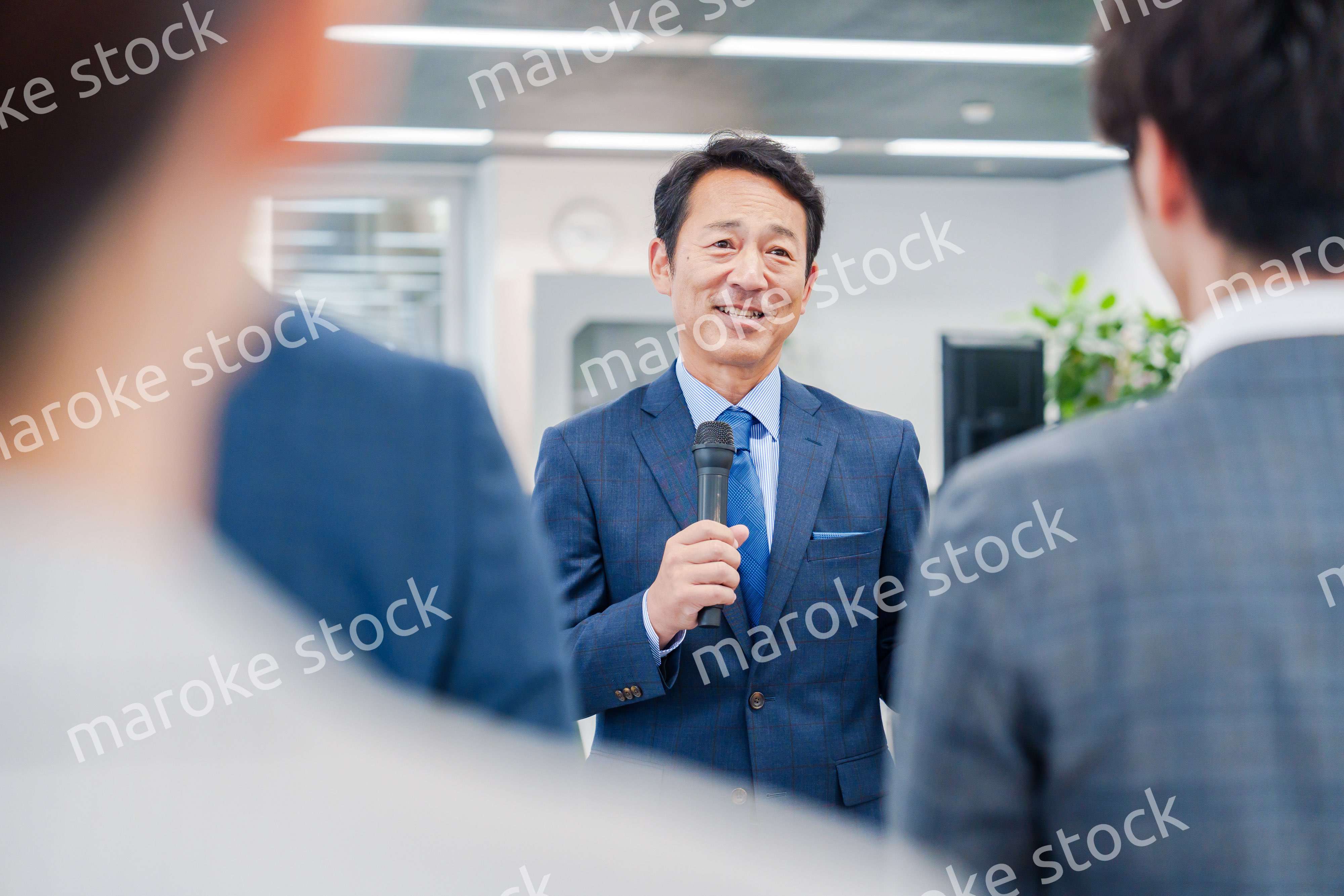 オフィスでの朝礼で挨拶をする管理職の男性