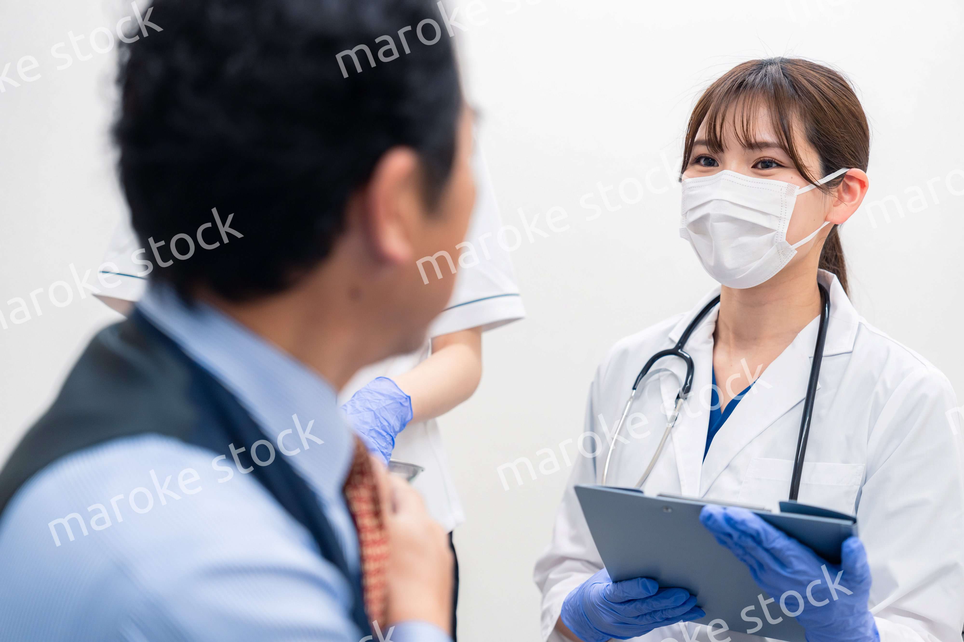 病院で男性患者の問診をする女性医師