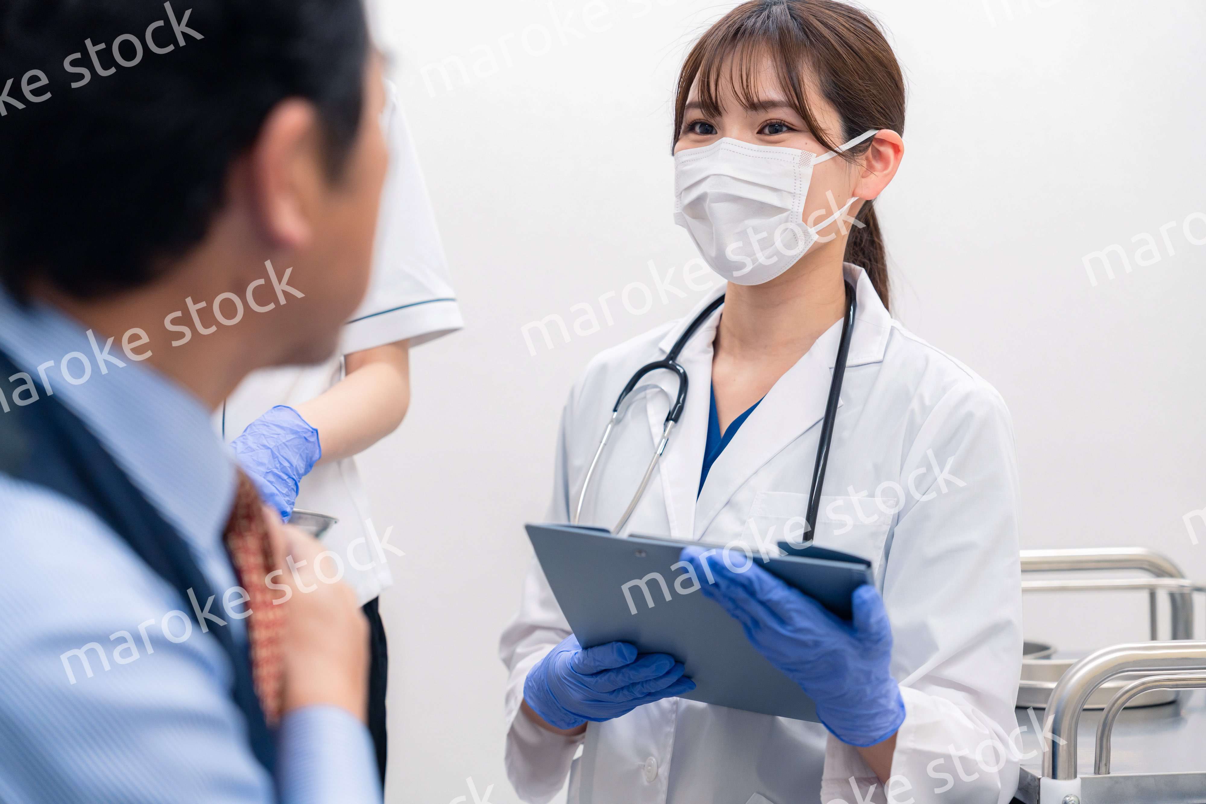 病院で男性患者の問診をする女性医師