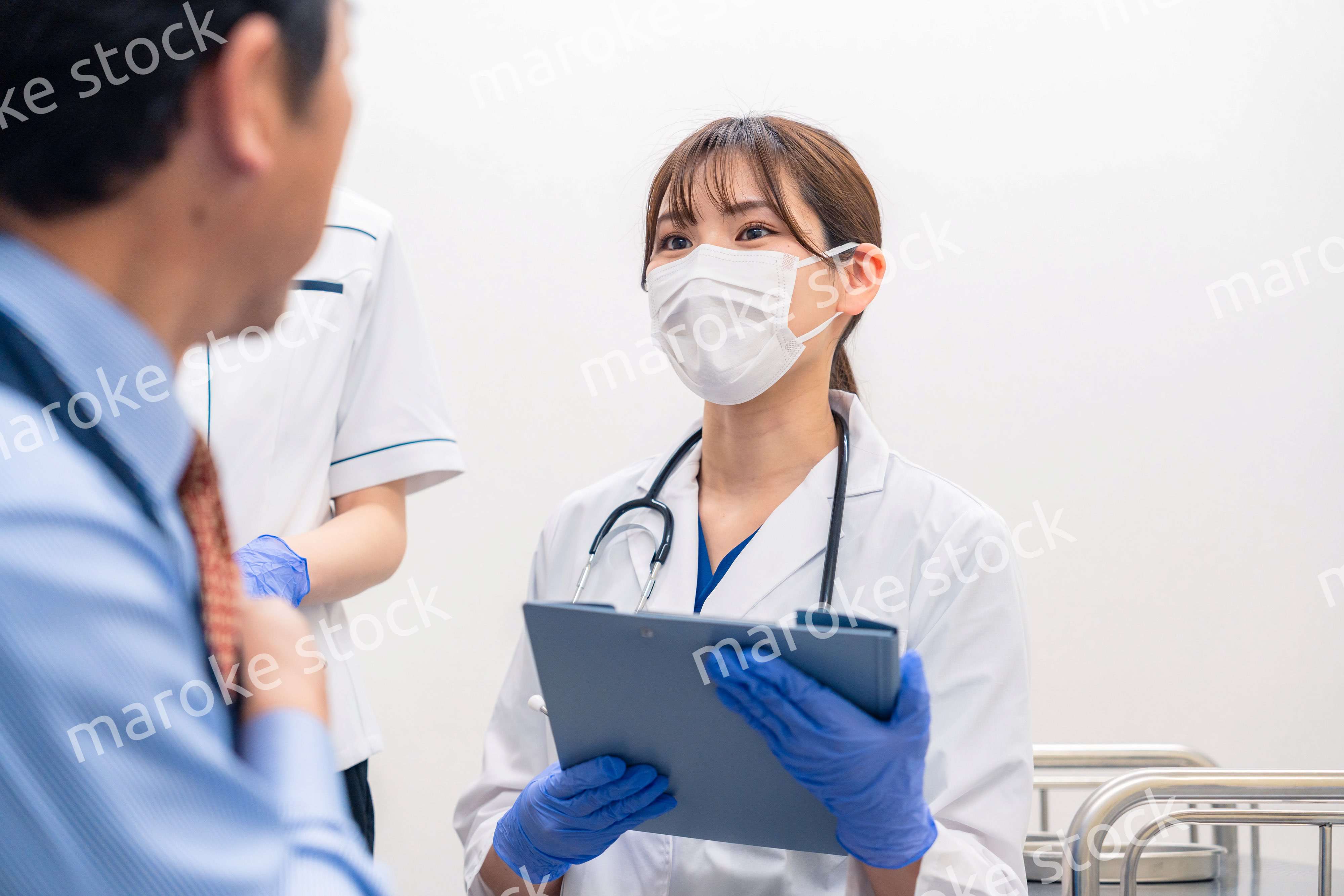 病院で男性患者の問診をする女性医師