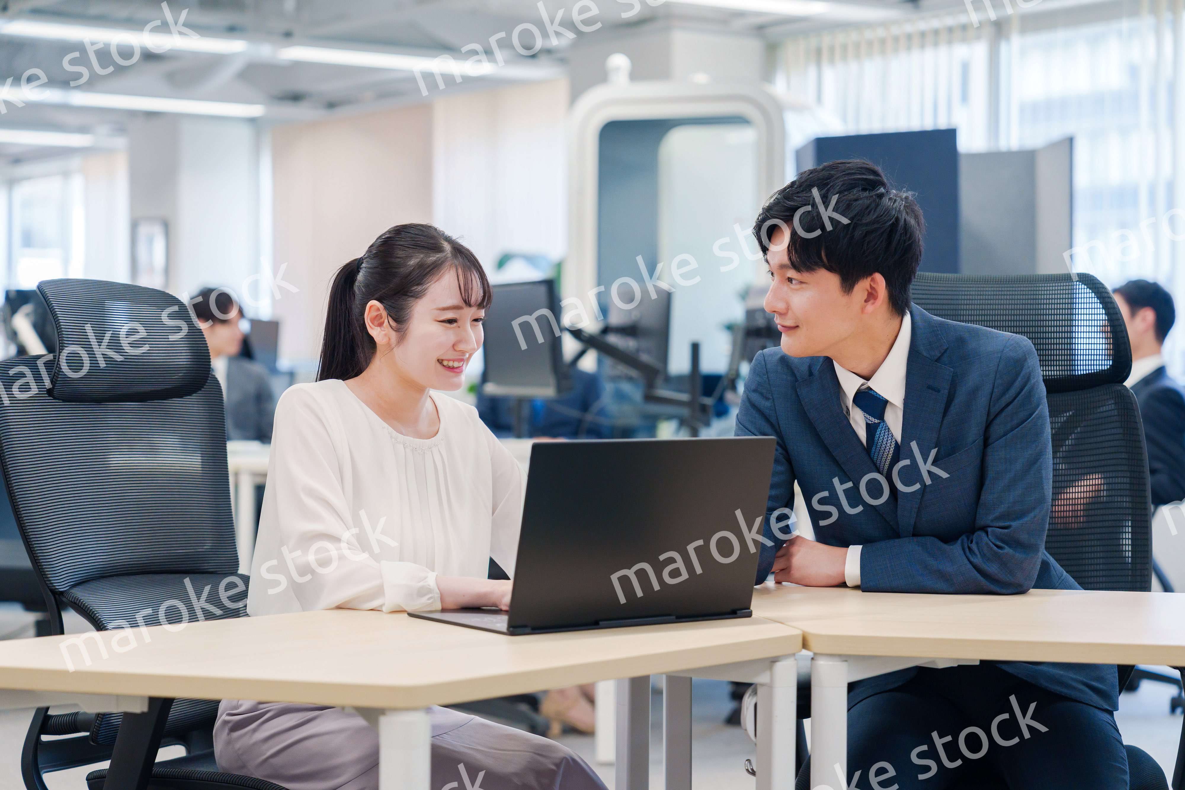 先輩社員から業務を教えてもらう新人の女性