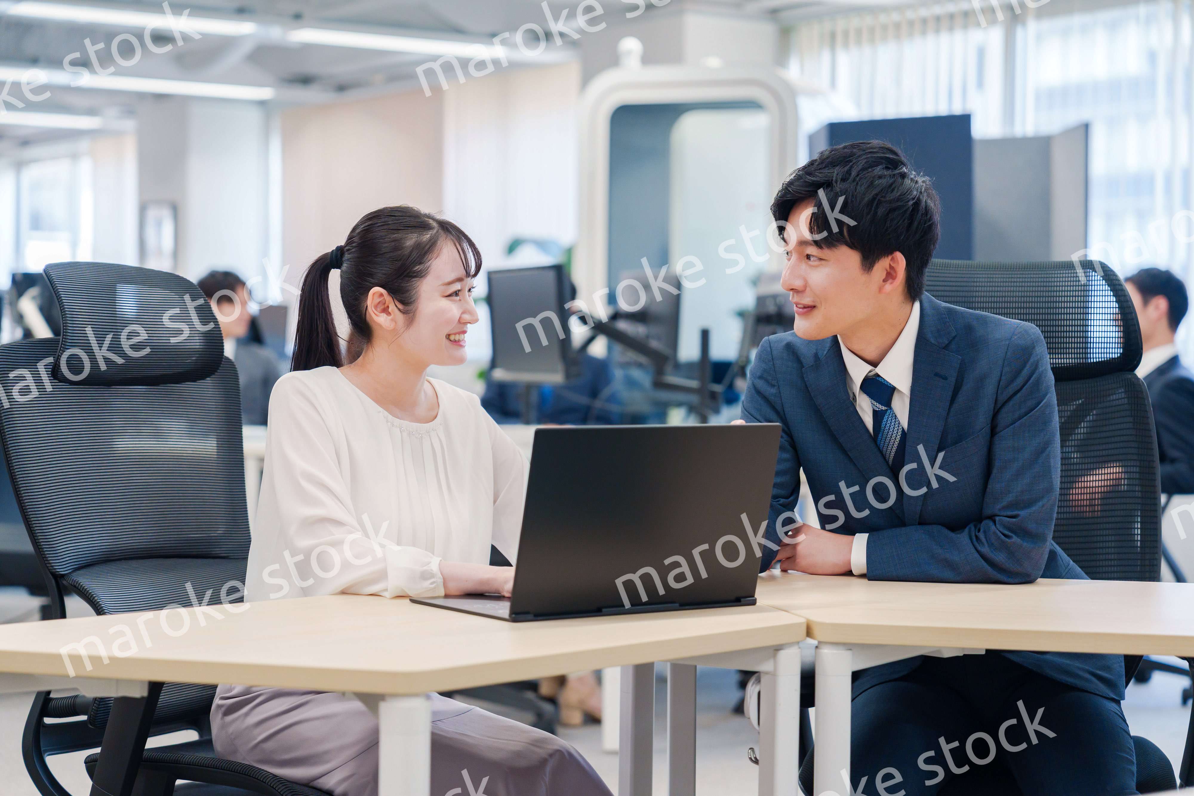 先輩社員から業務を教えてもらう新人の女性