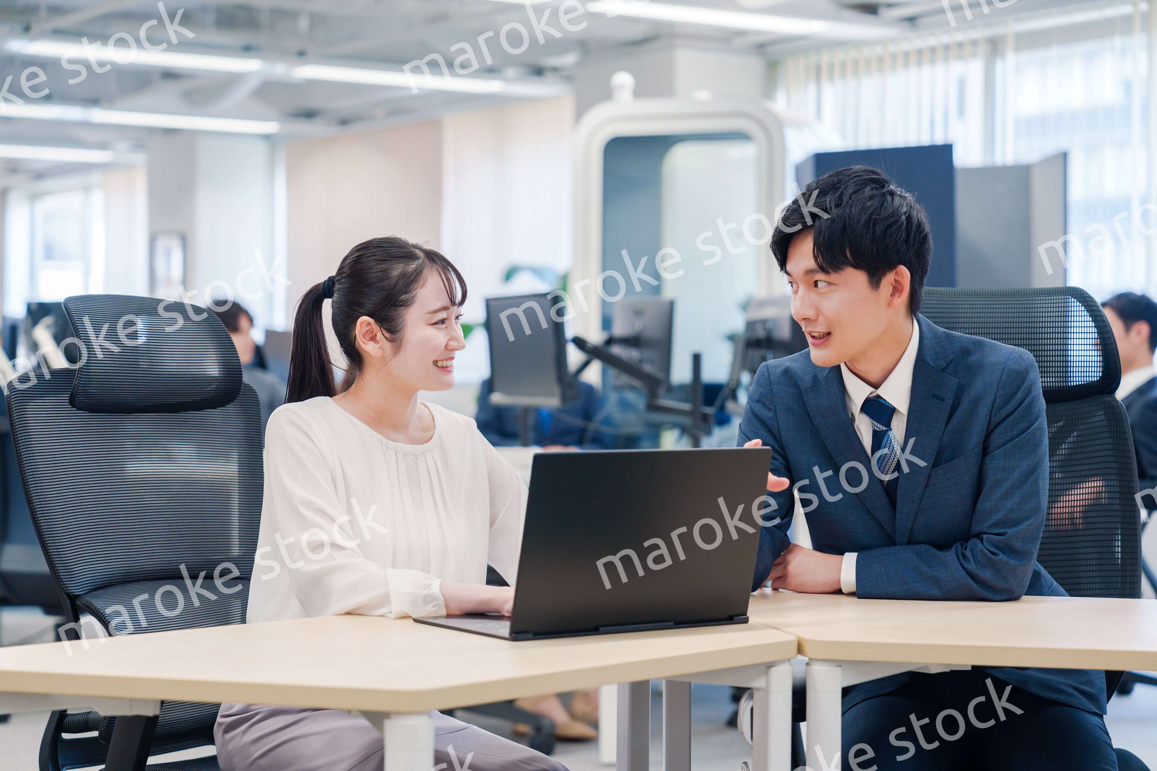 先輩社員から業務を教えてもらう新人の女性