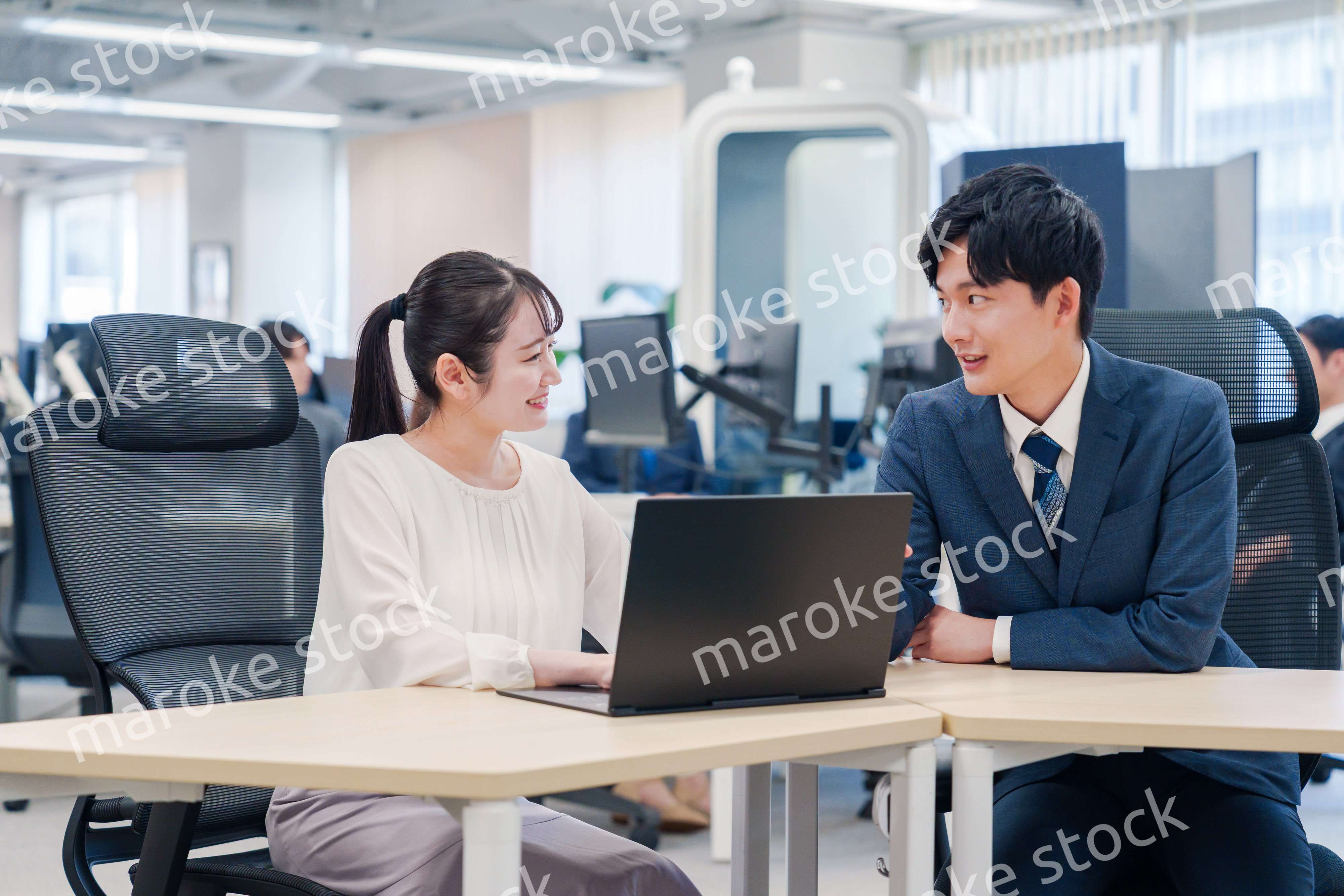 先輩社員から業務を教えてもらう新人の女性