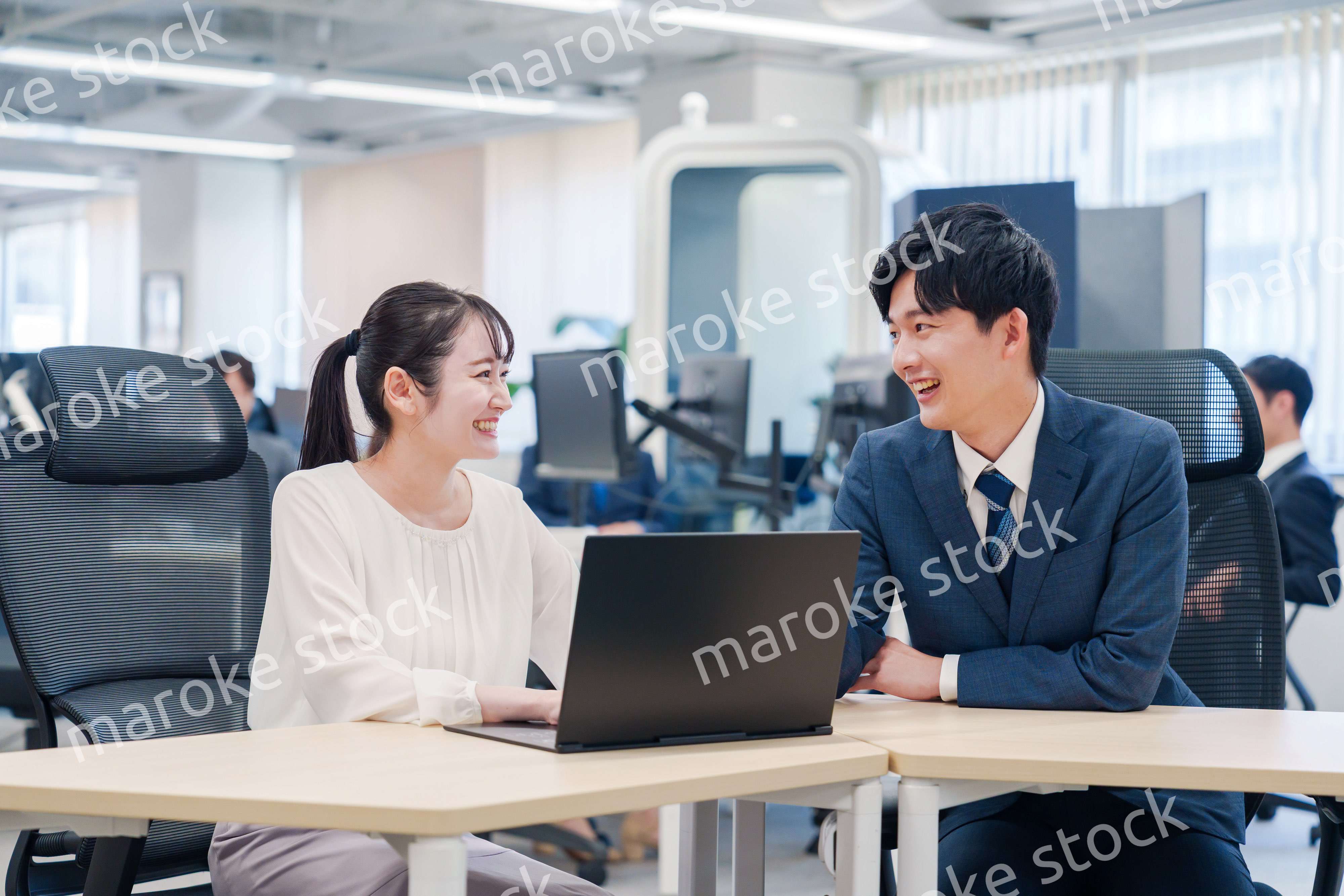 先輩社員から業務を教えてもらう新人の女性