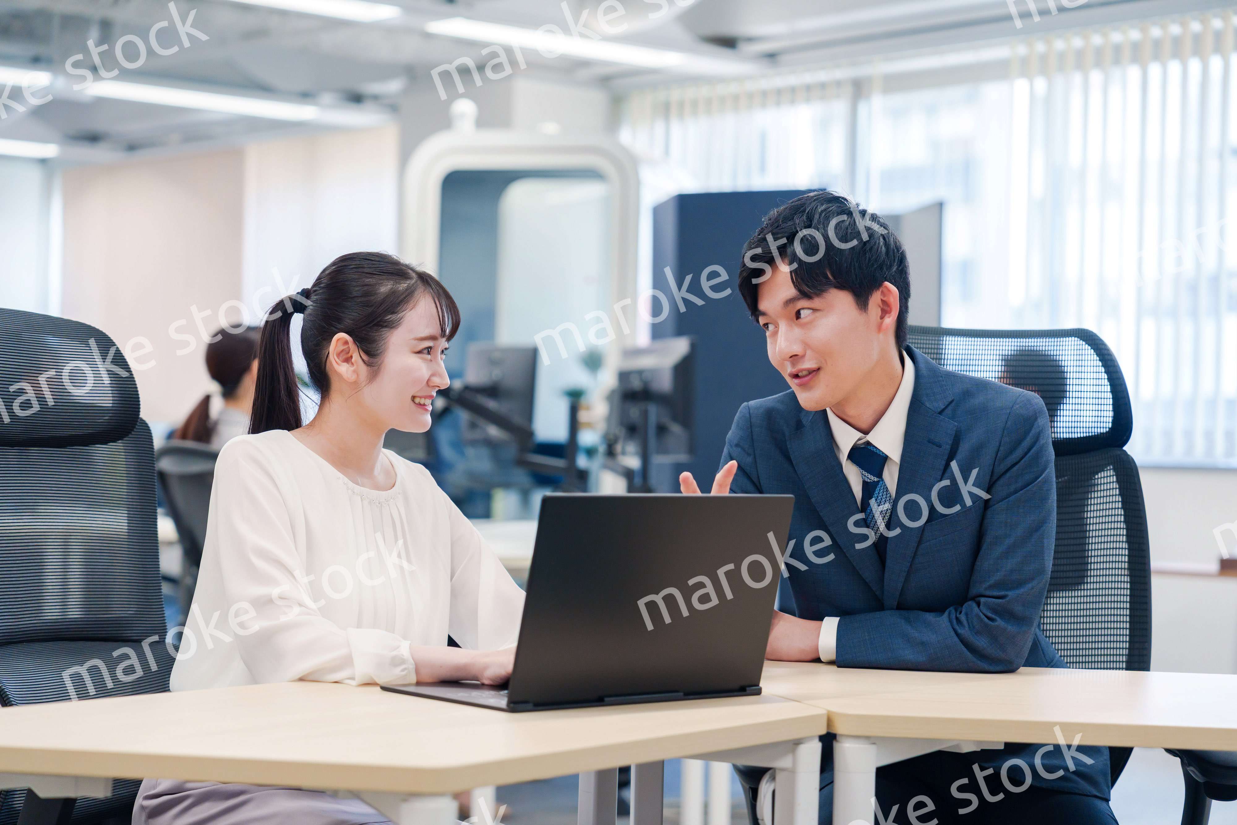 先輩社員から業務を教えてもらう新人の女性