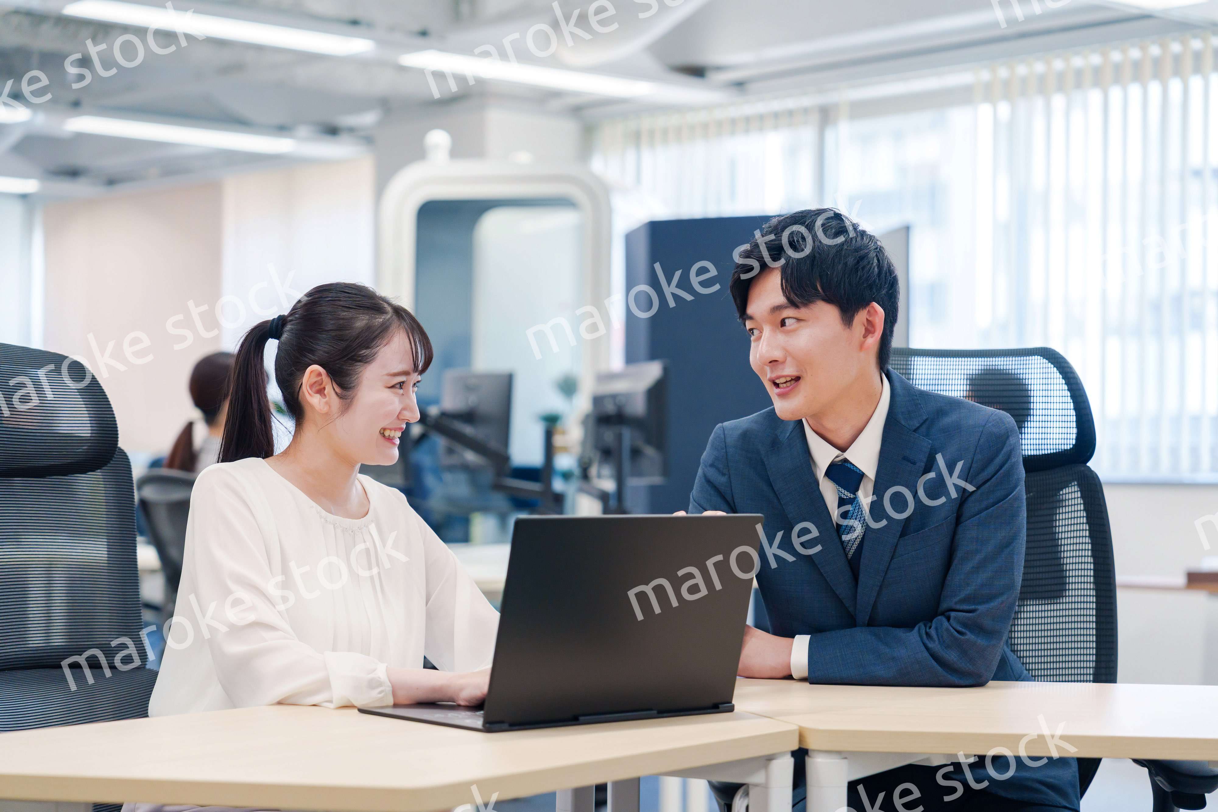 先輩社員から業務を教えてもらう新人の女性