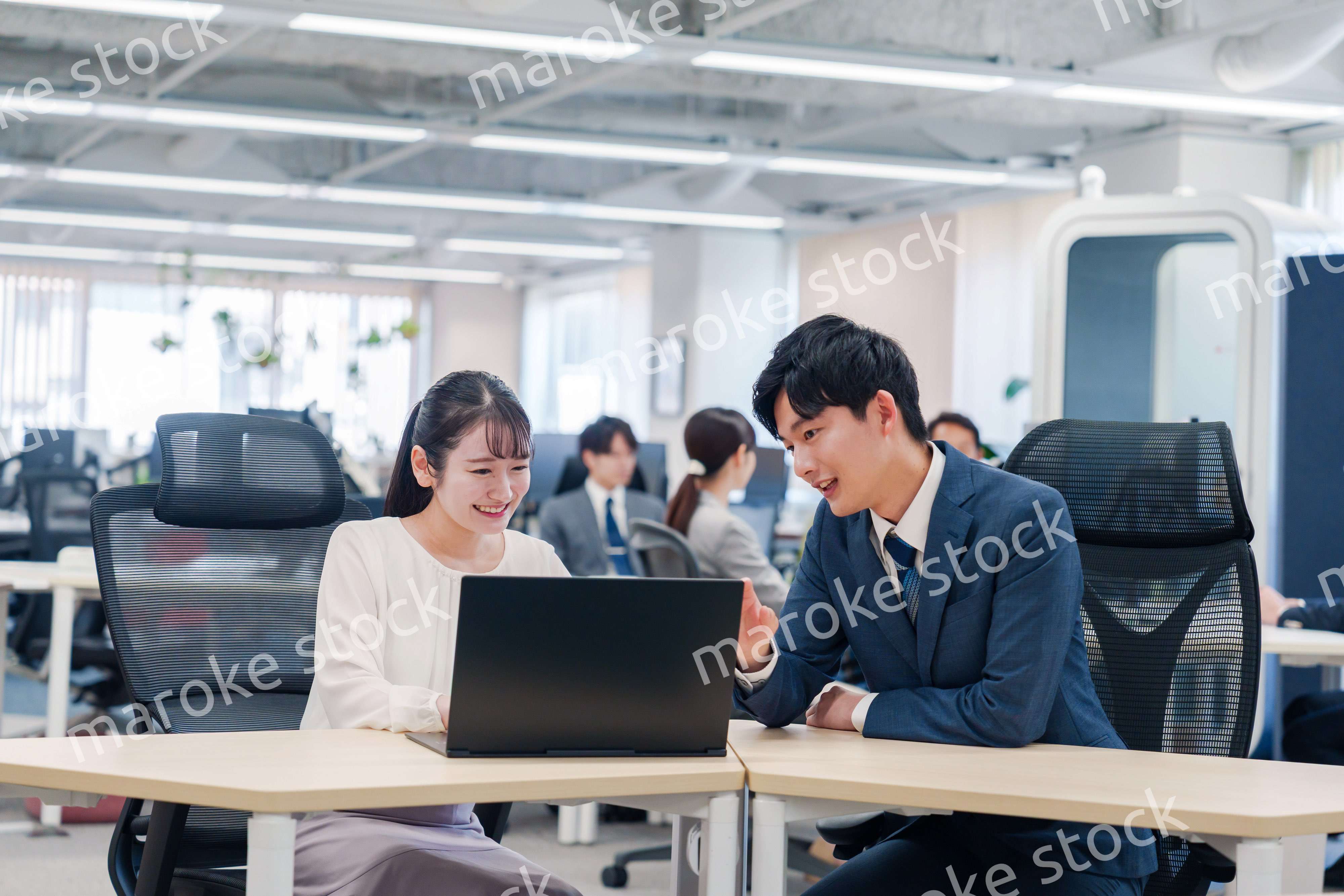 先輩社員から業務を教えてもらう新人の女性